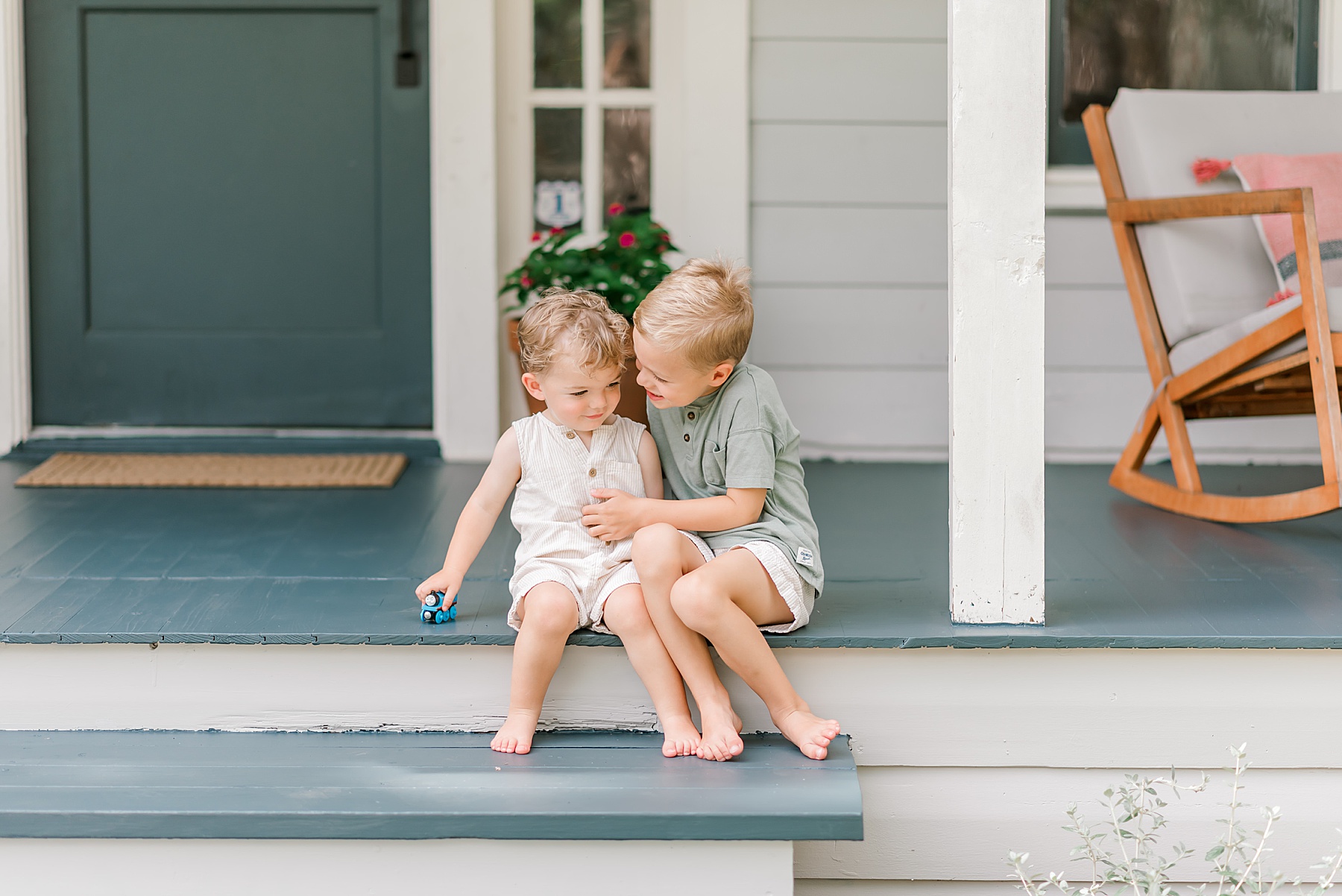 brothers sit on front porch of home during family session 