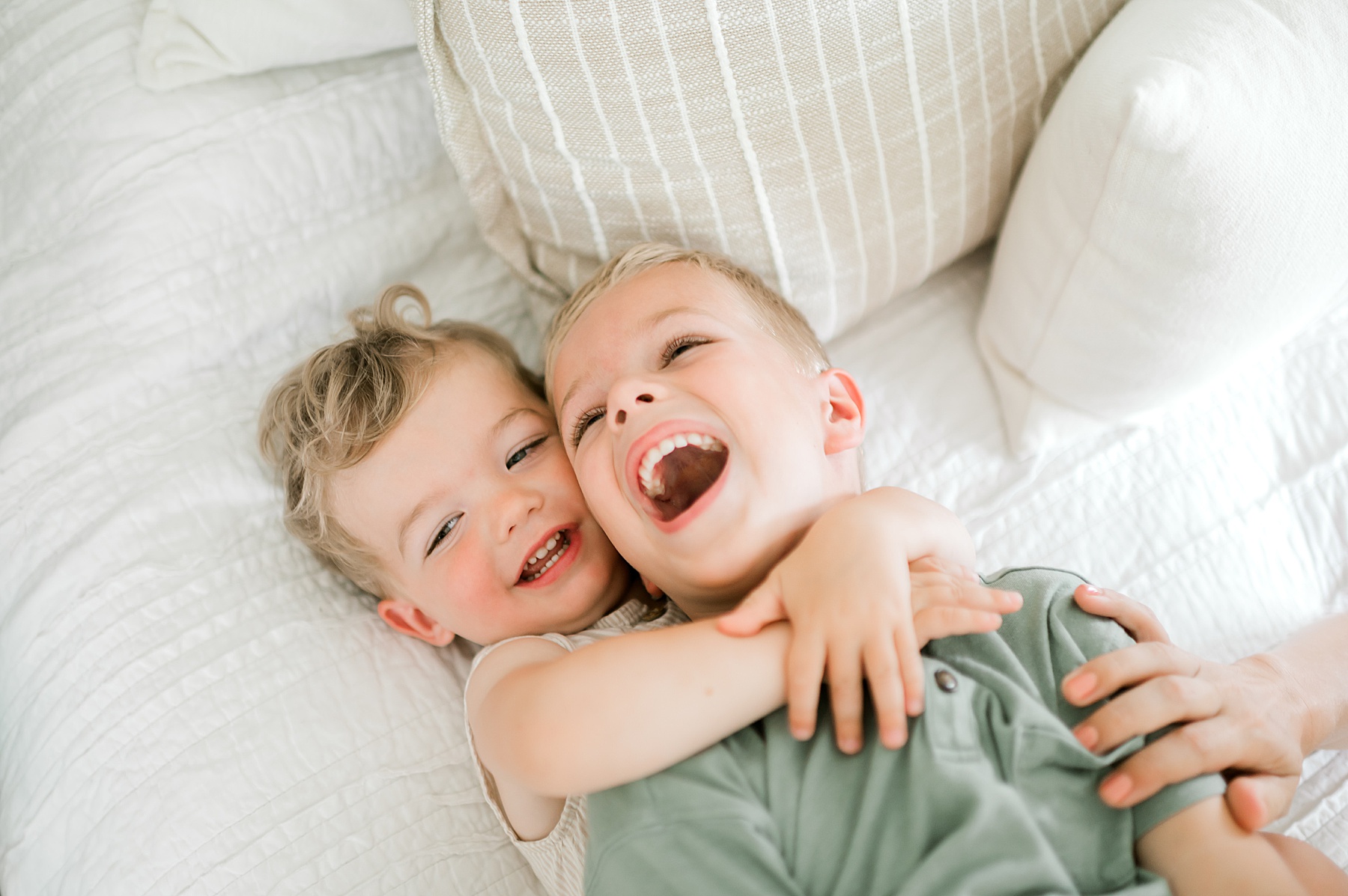 brothers laughing and hugging on bed 