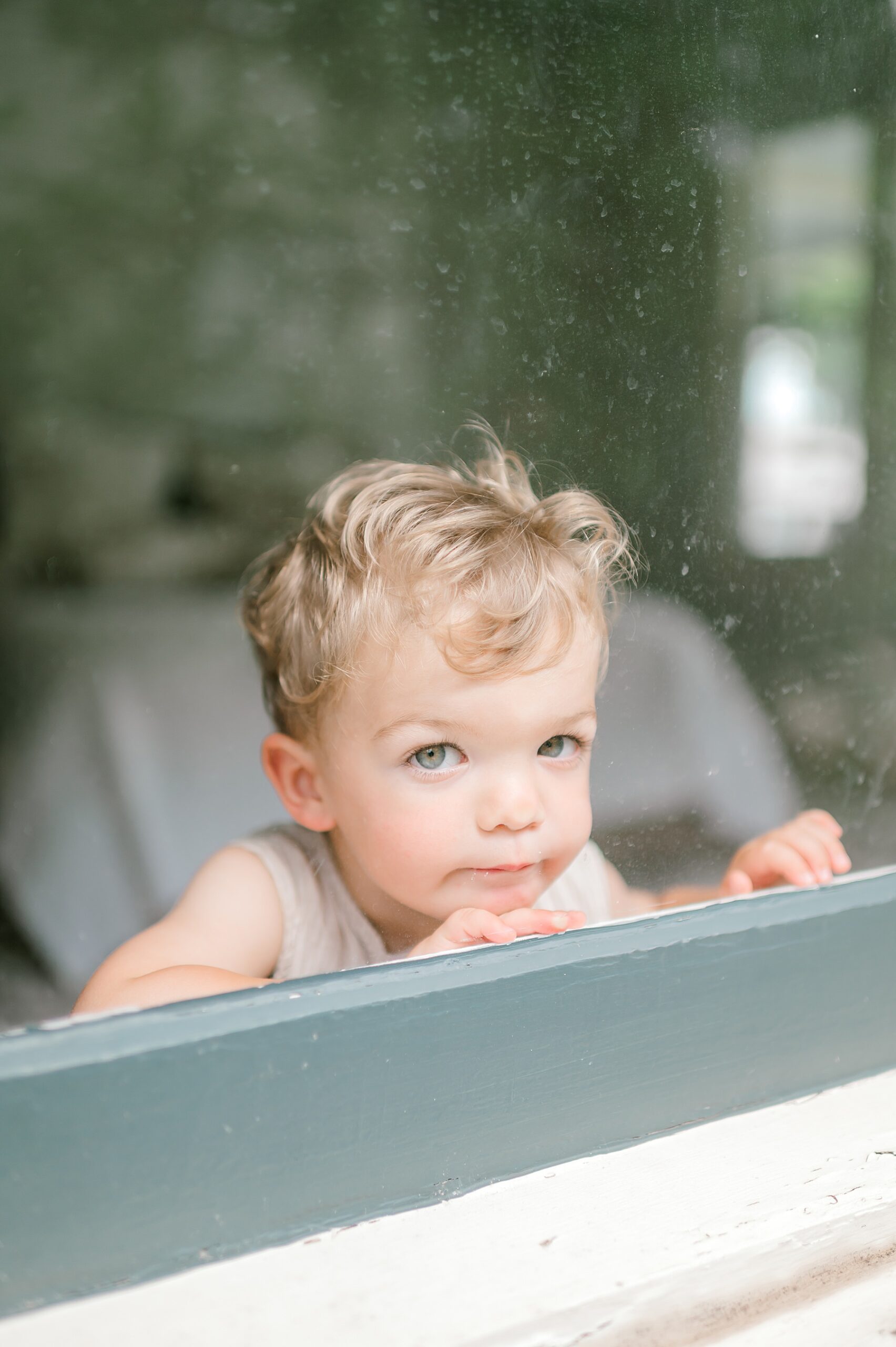little boy looks out window of family home