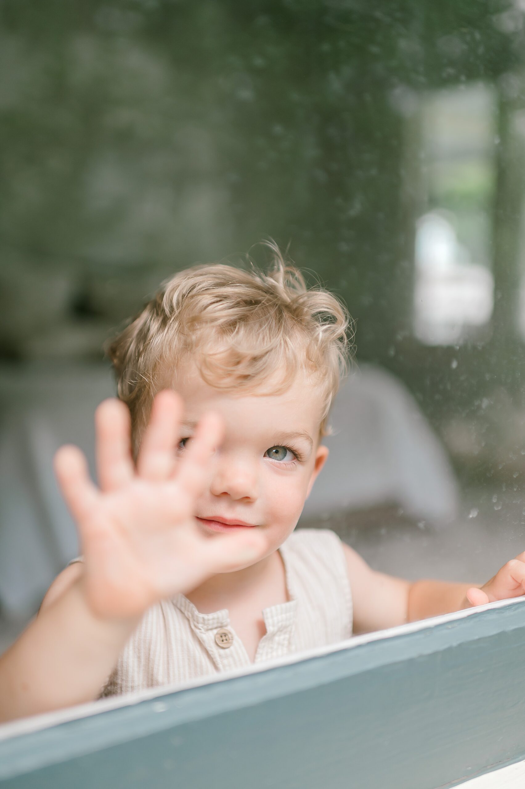 young boy waves out the window