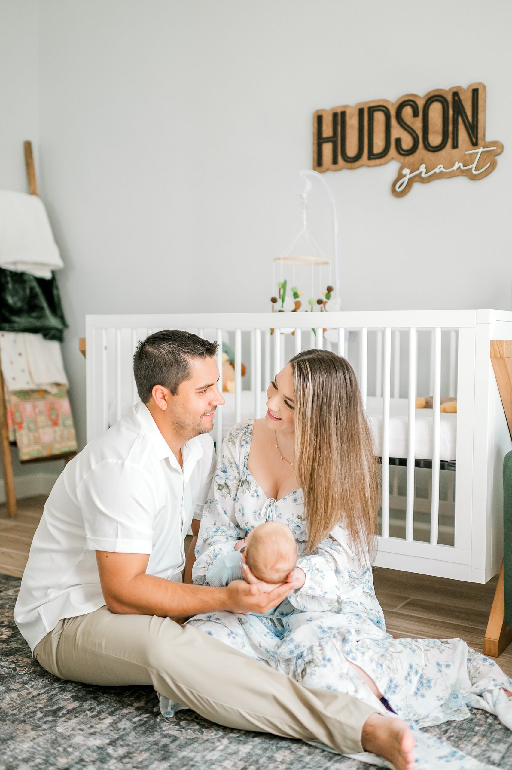 parents sit on nursery floor holding baby boy