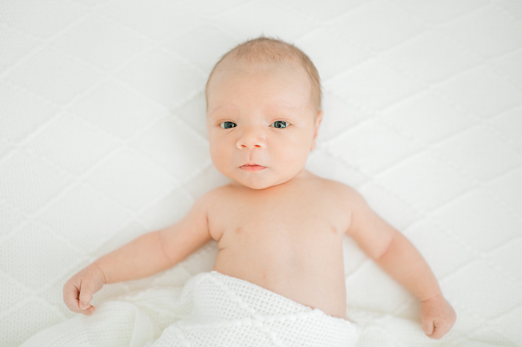 newborn lays with white knit blanket 