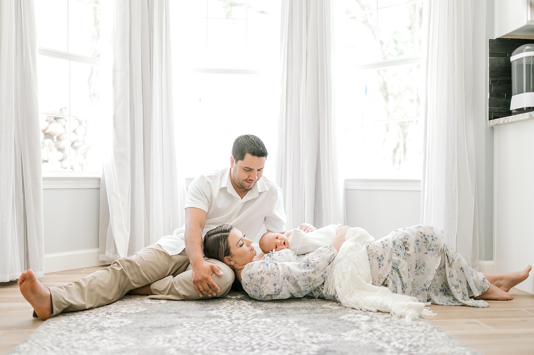 tender moments between family as mom lays her head in husband's lap while holding newborn on chest