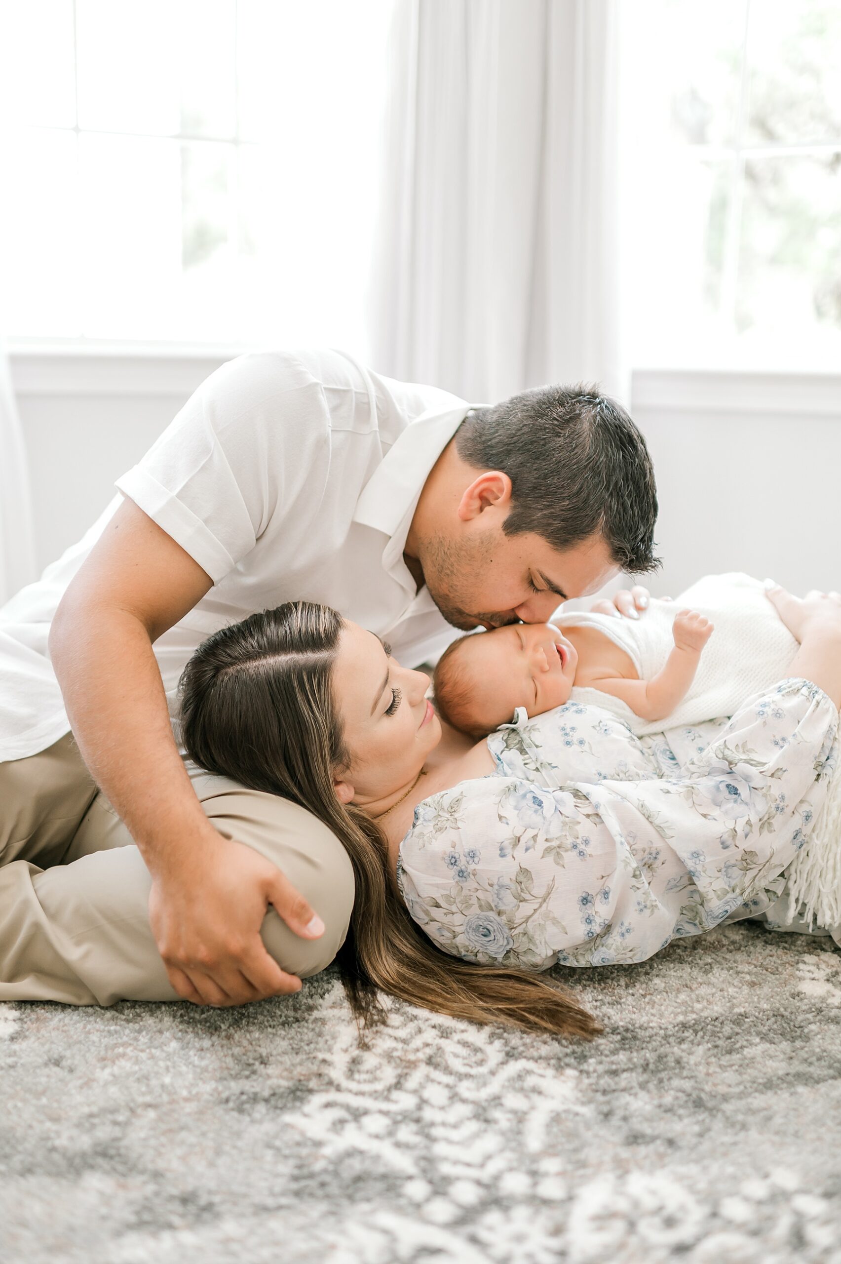 newborn lays on mom's chest and dad leans over to kiss baby's head | Styling Tips for Newborn Sessions
