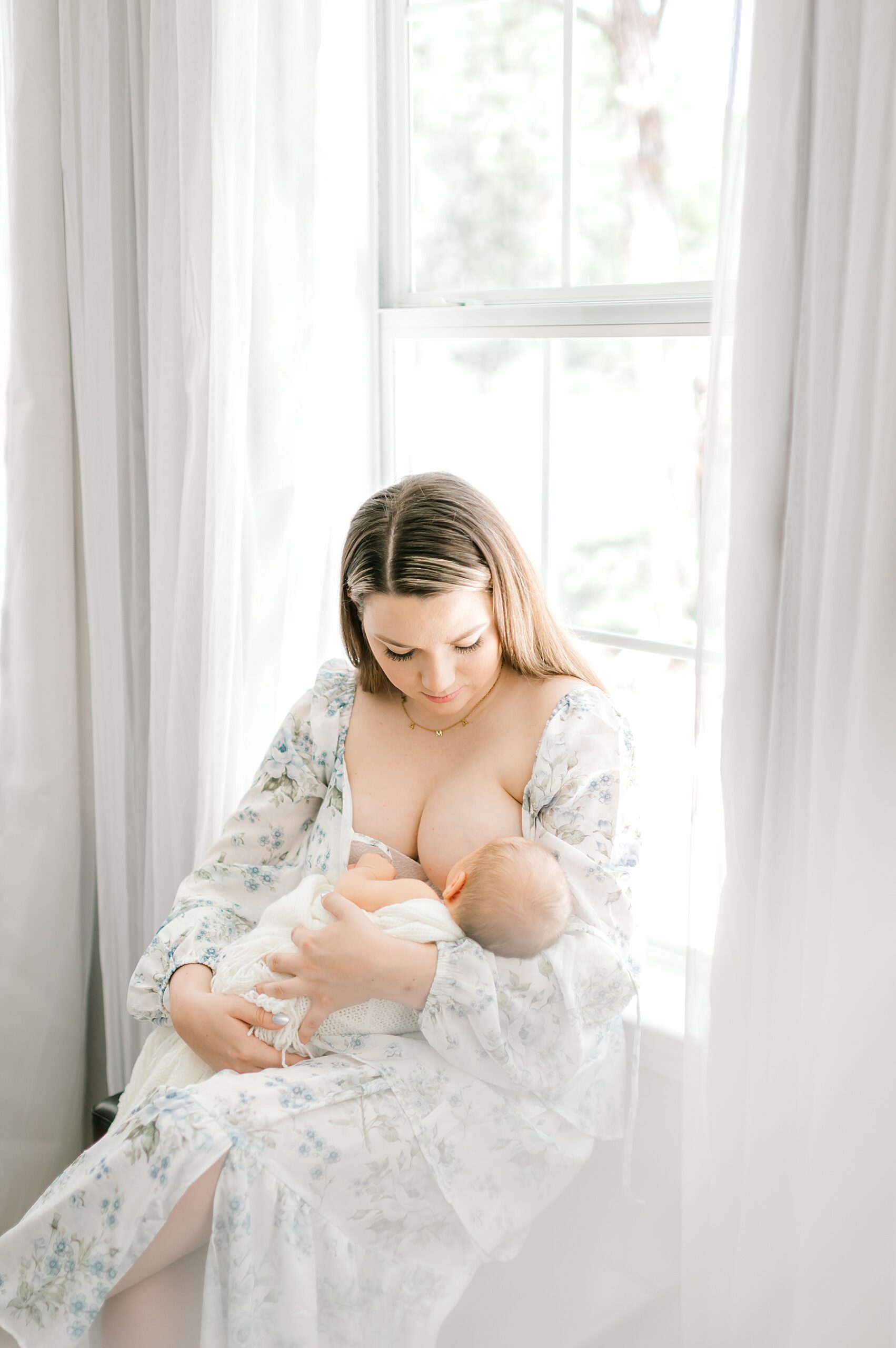 mom feeds newborn during lifestyle in-home session
