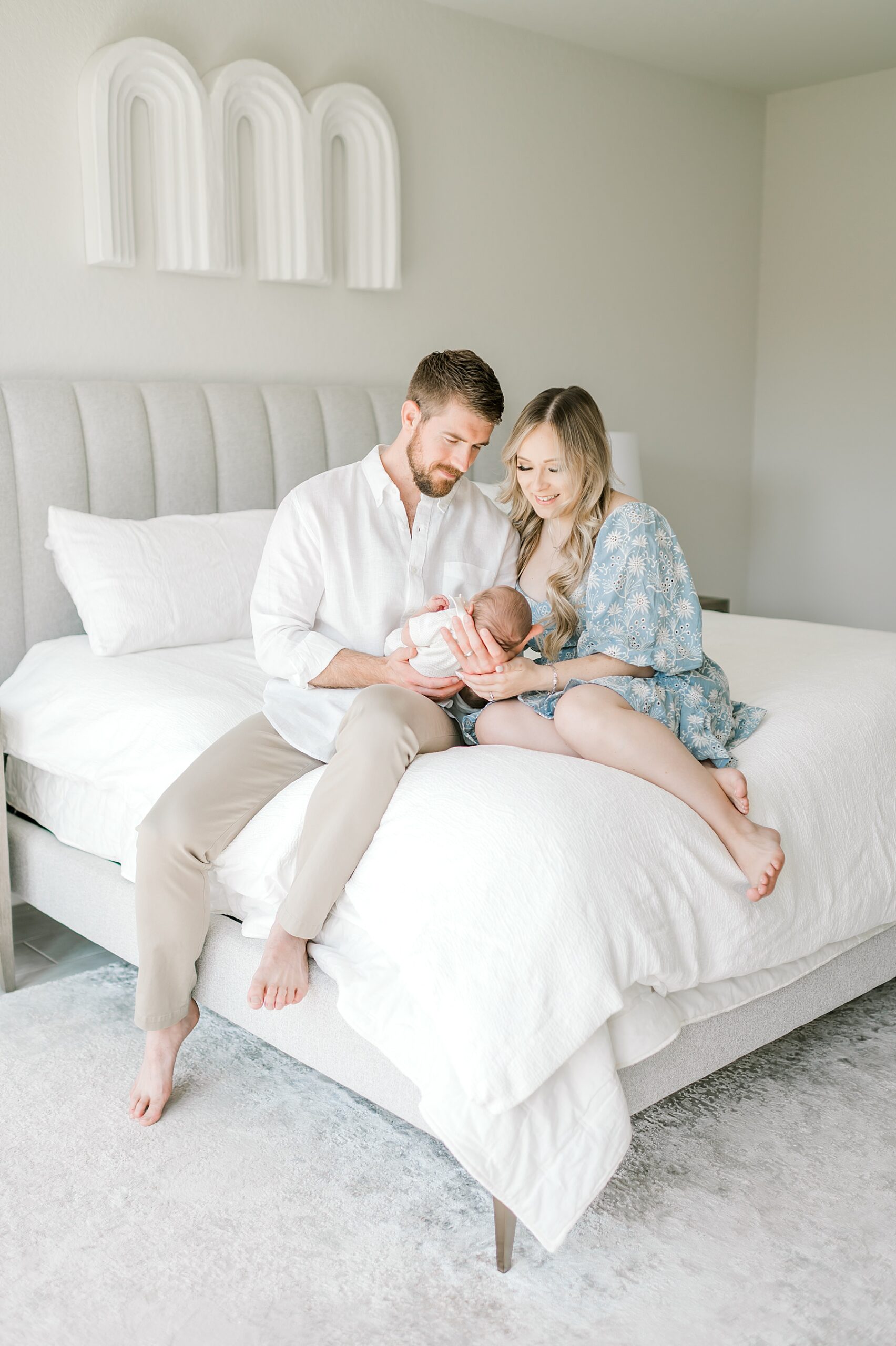 parents sit with newborn on bed