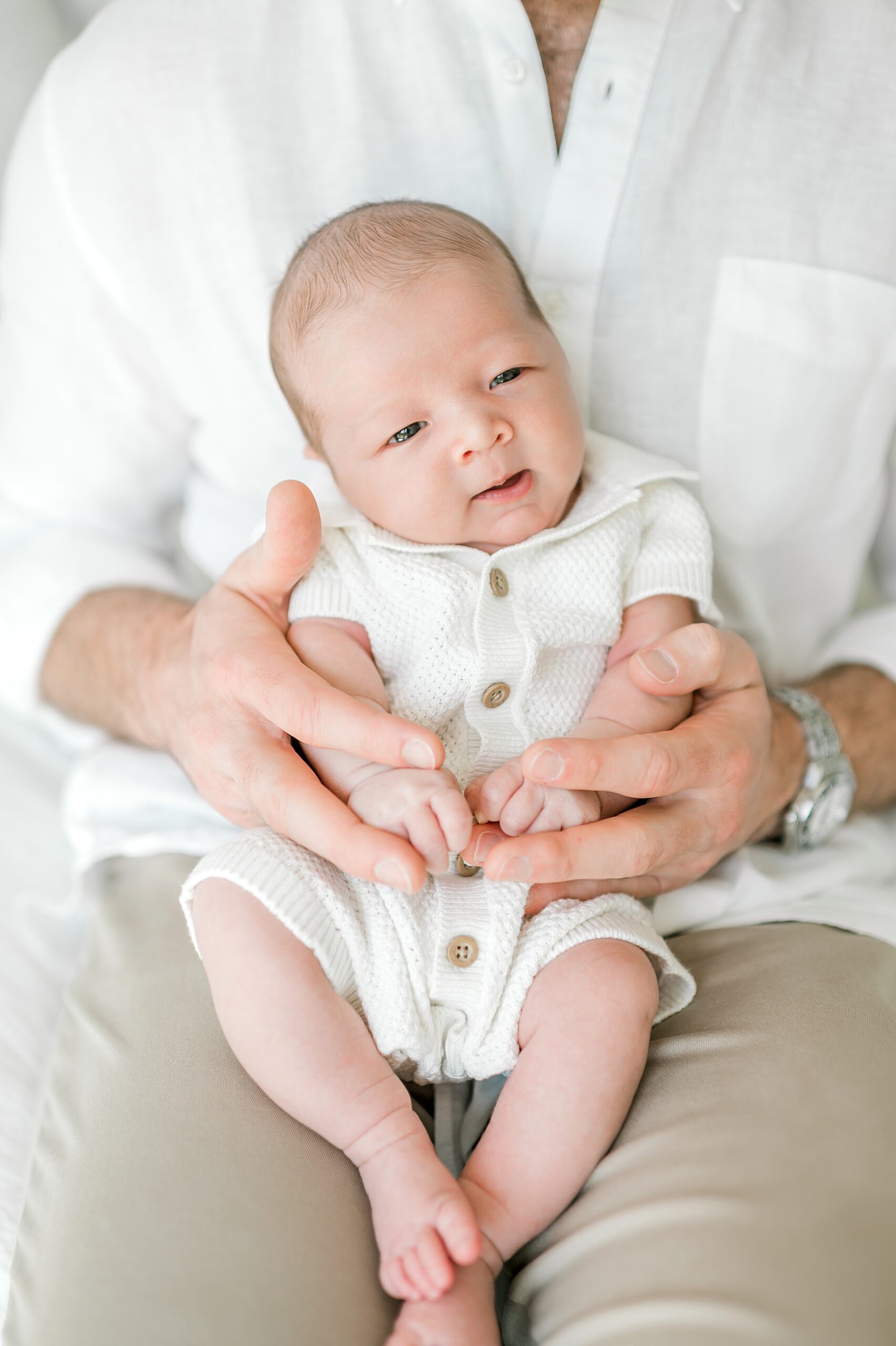 Newborn boy sits in dad's lap