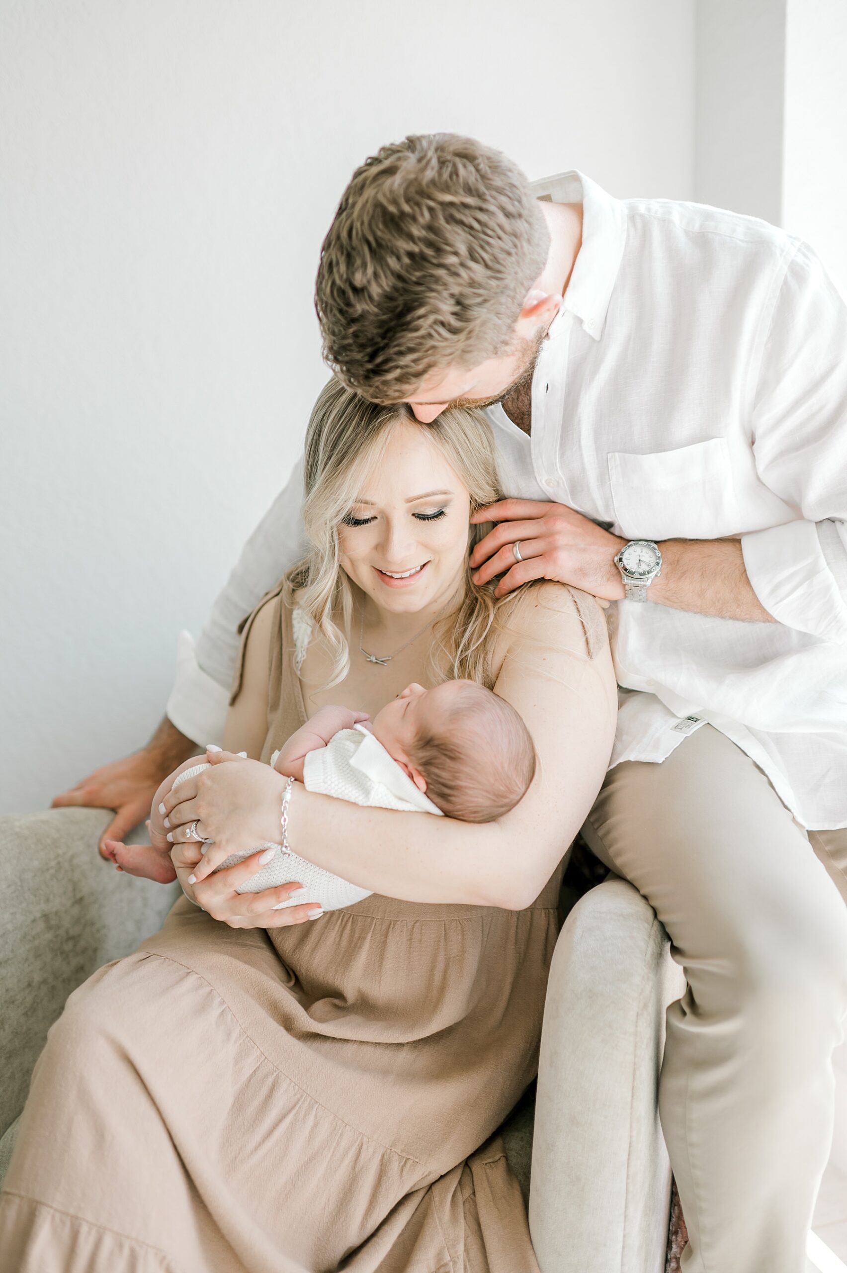 dad kisses mom's head as she holds newborn