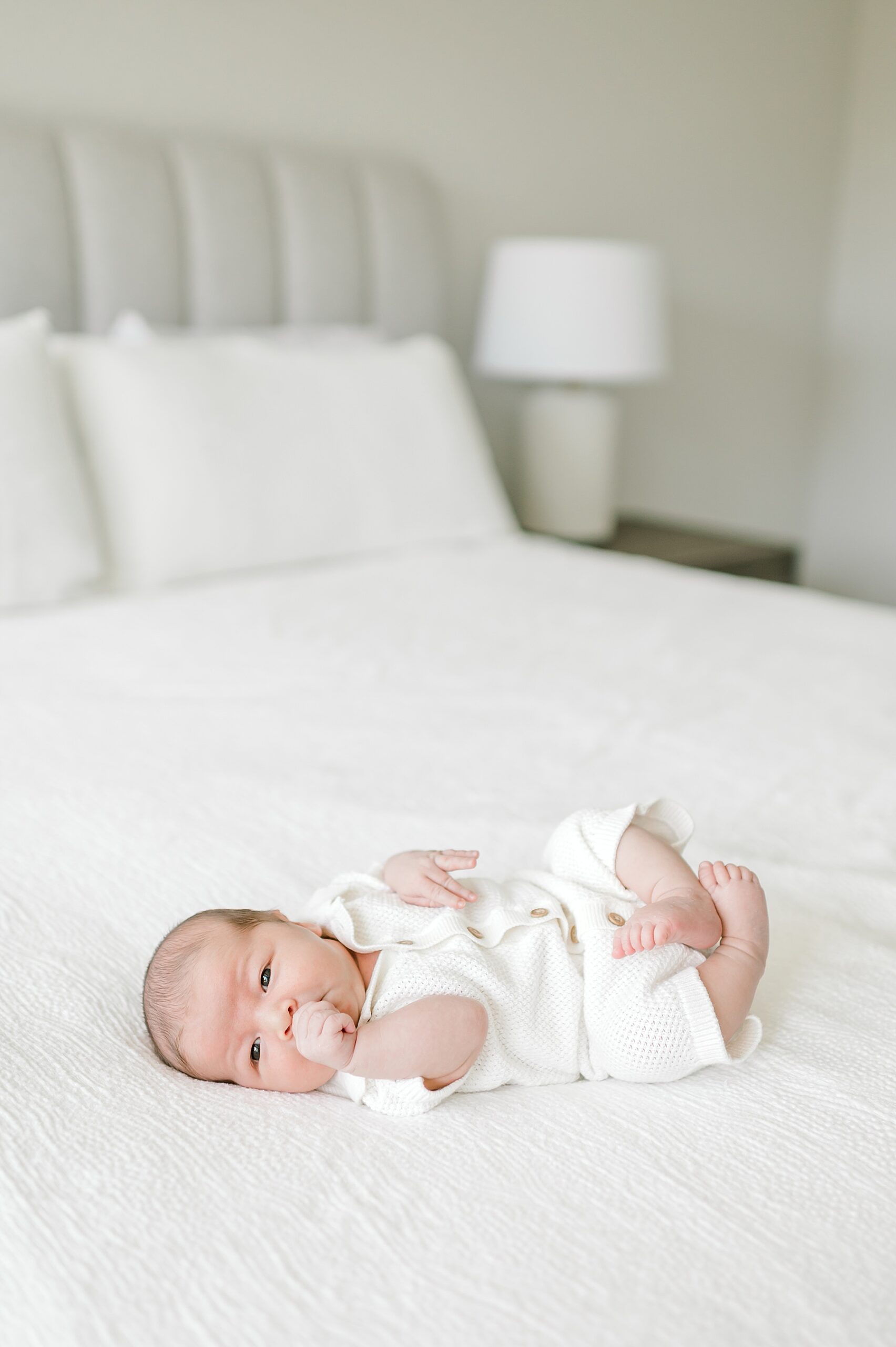 awake newborn boy on white bed | Top 5 Questions To Ask Your Newborn Photographer