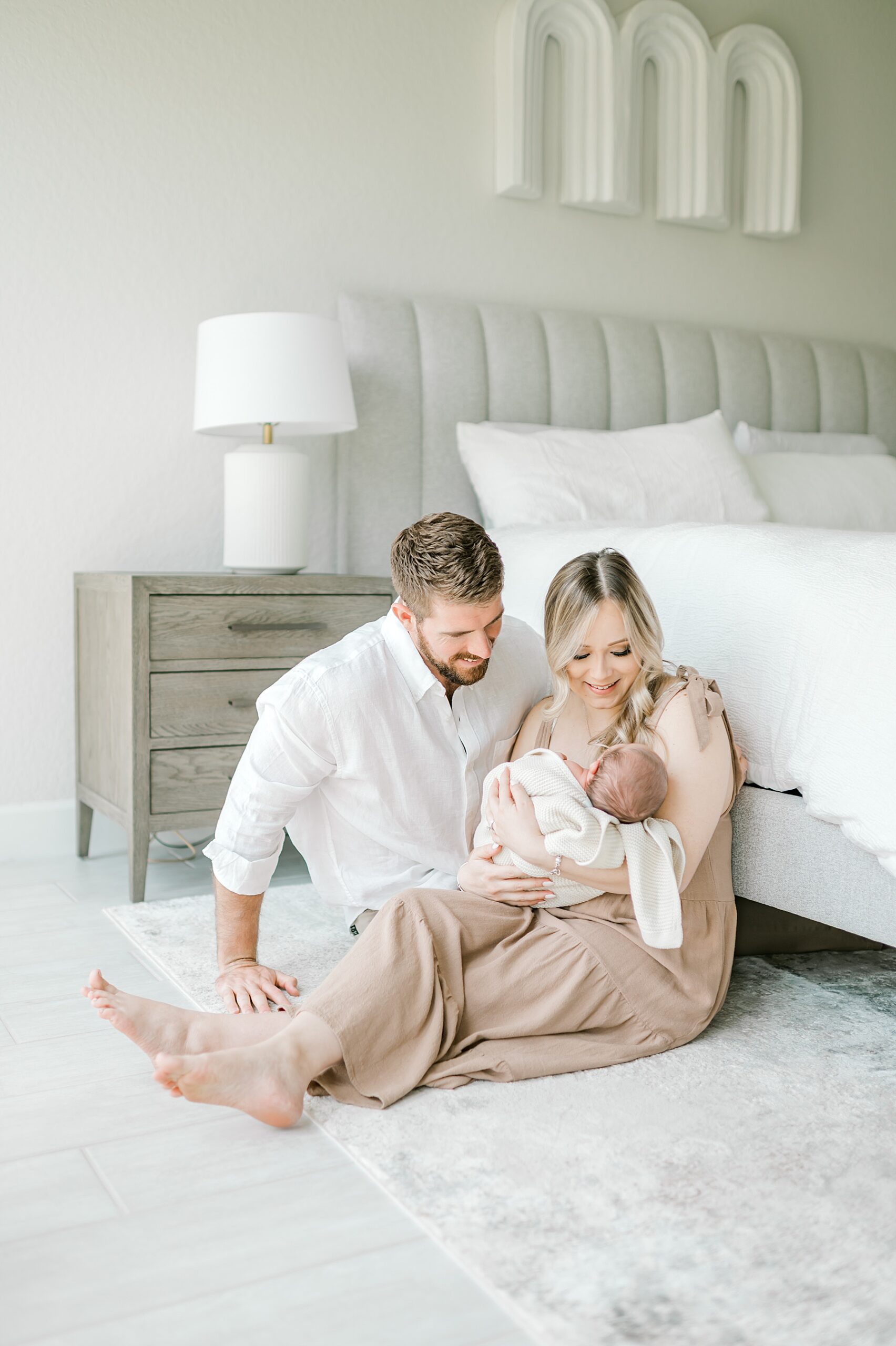 new parents sit on floor holding newborn