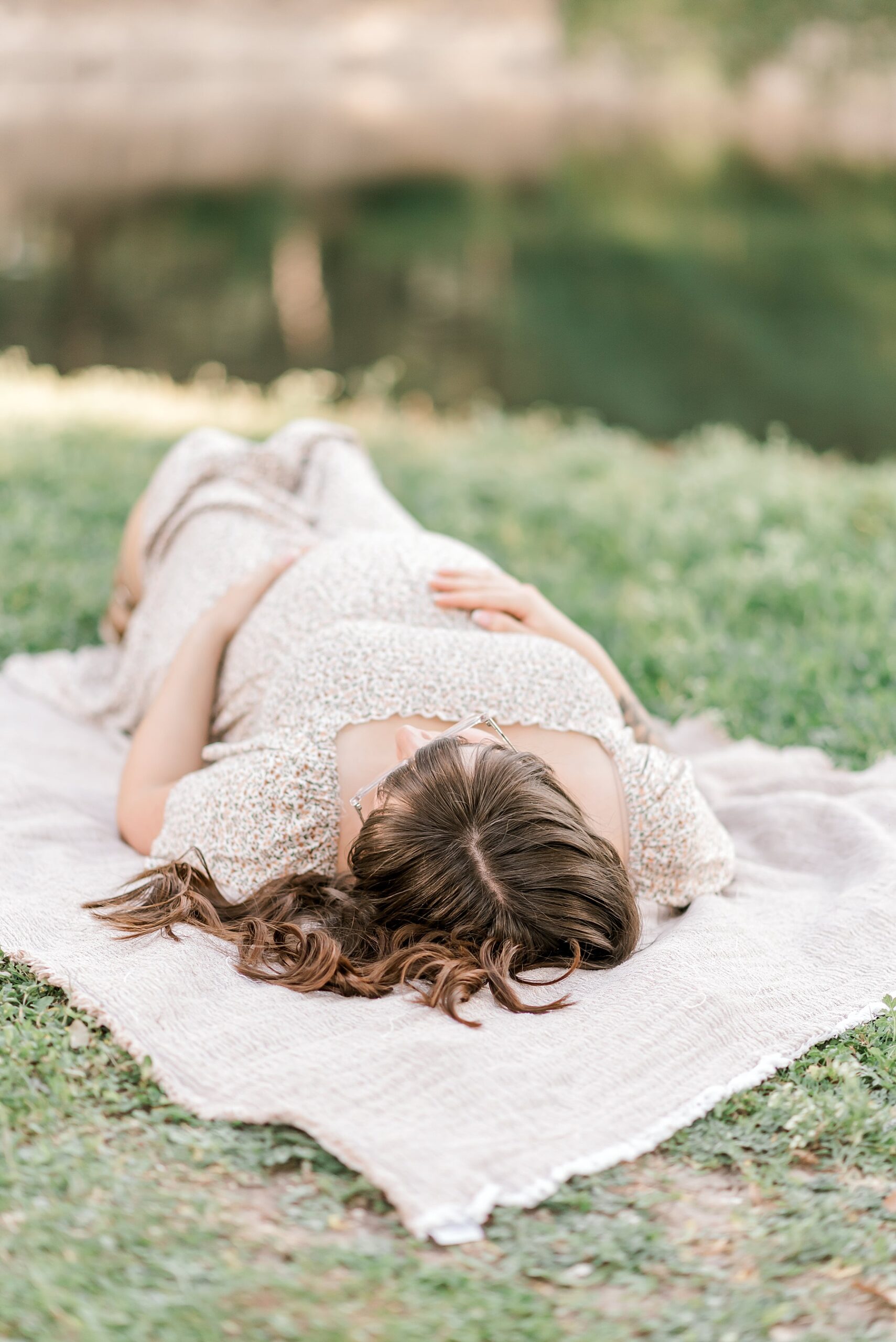 Expectant mother lays on blanket in the grass | Celebrating the Journey to Motherhood 
