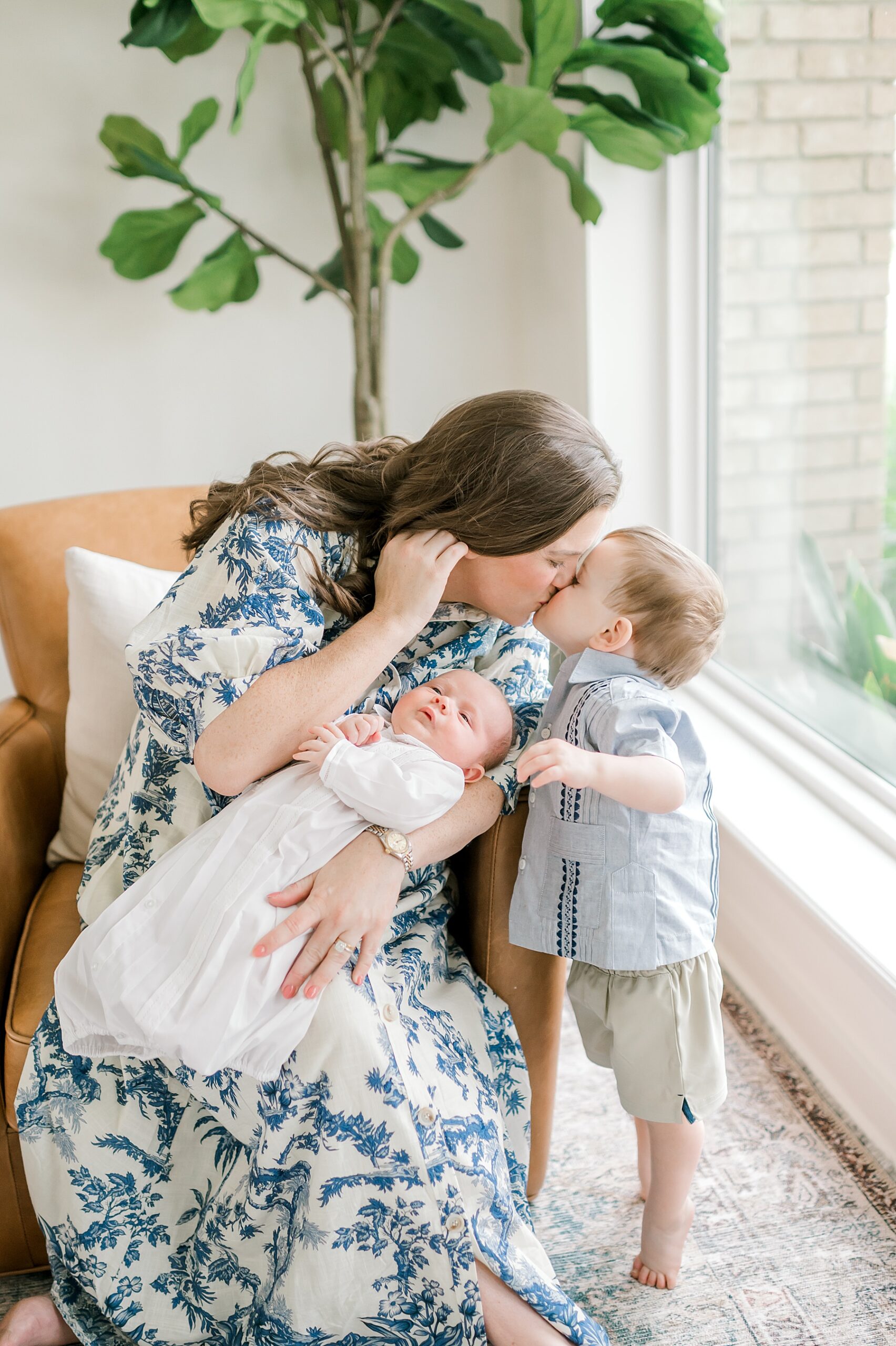 mom kisses oldest son while holding newborn 