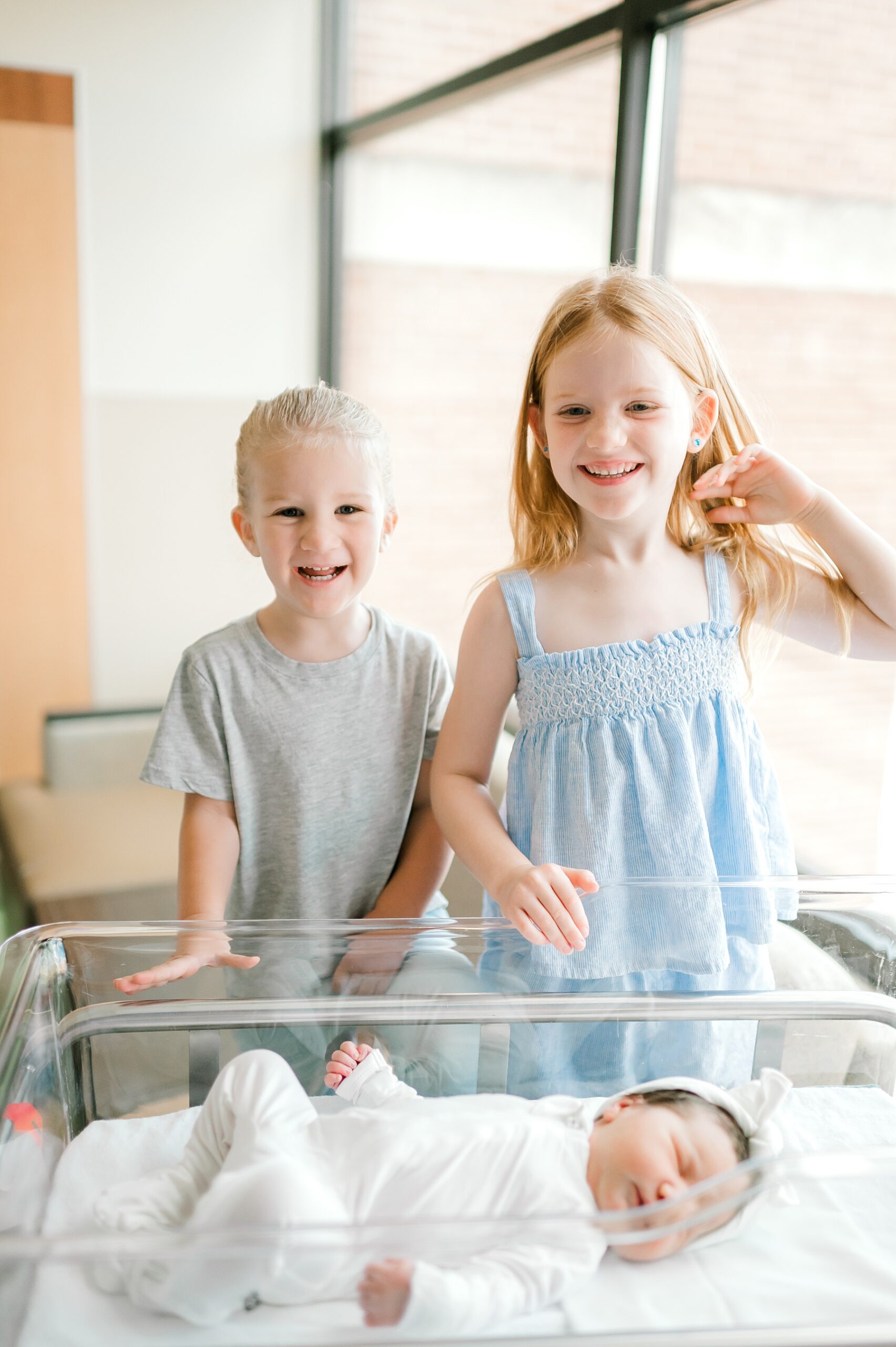 siblings with newborn in white outfit 