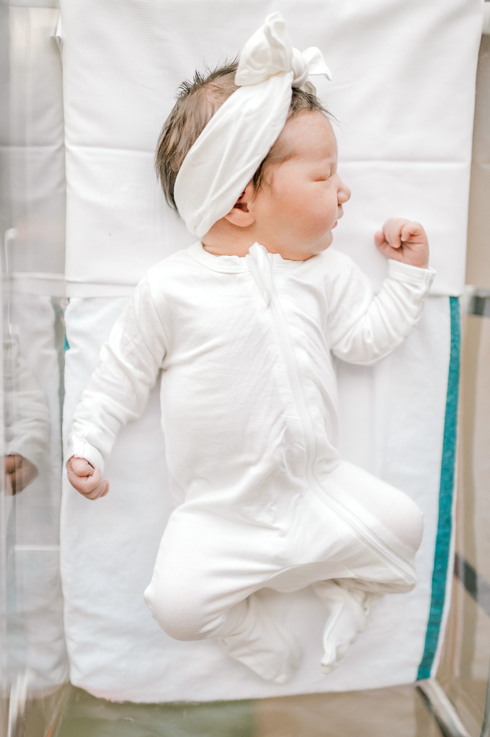 newborn girl in white outfit and matching headband bow