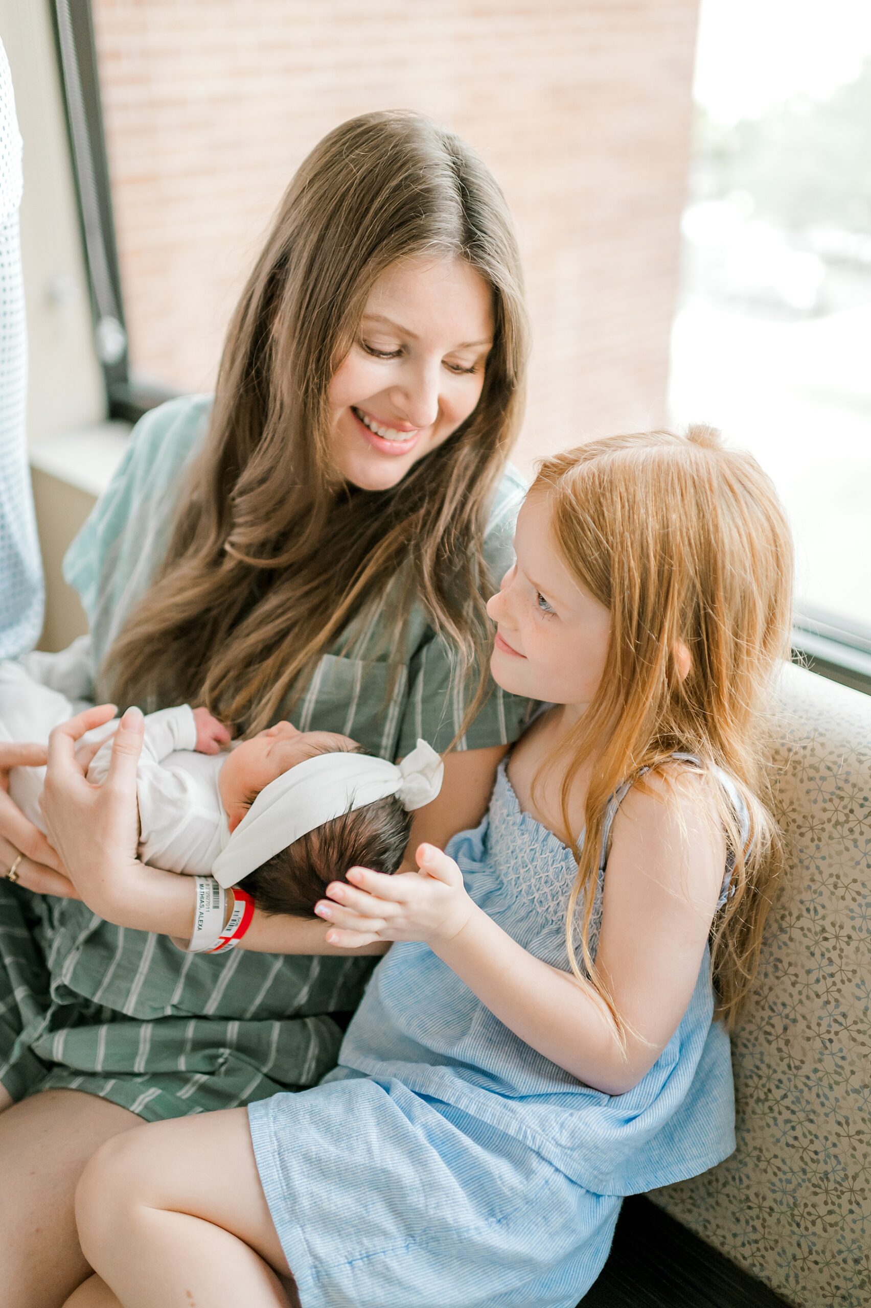 mom holds newborn with big sister nearby