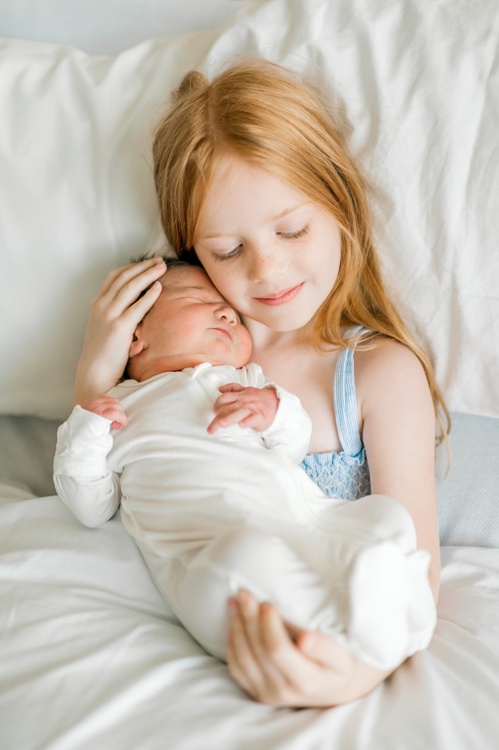 big sister holds newborn sister close 