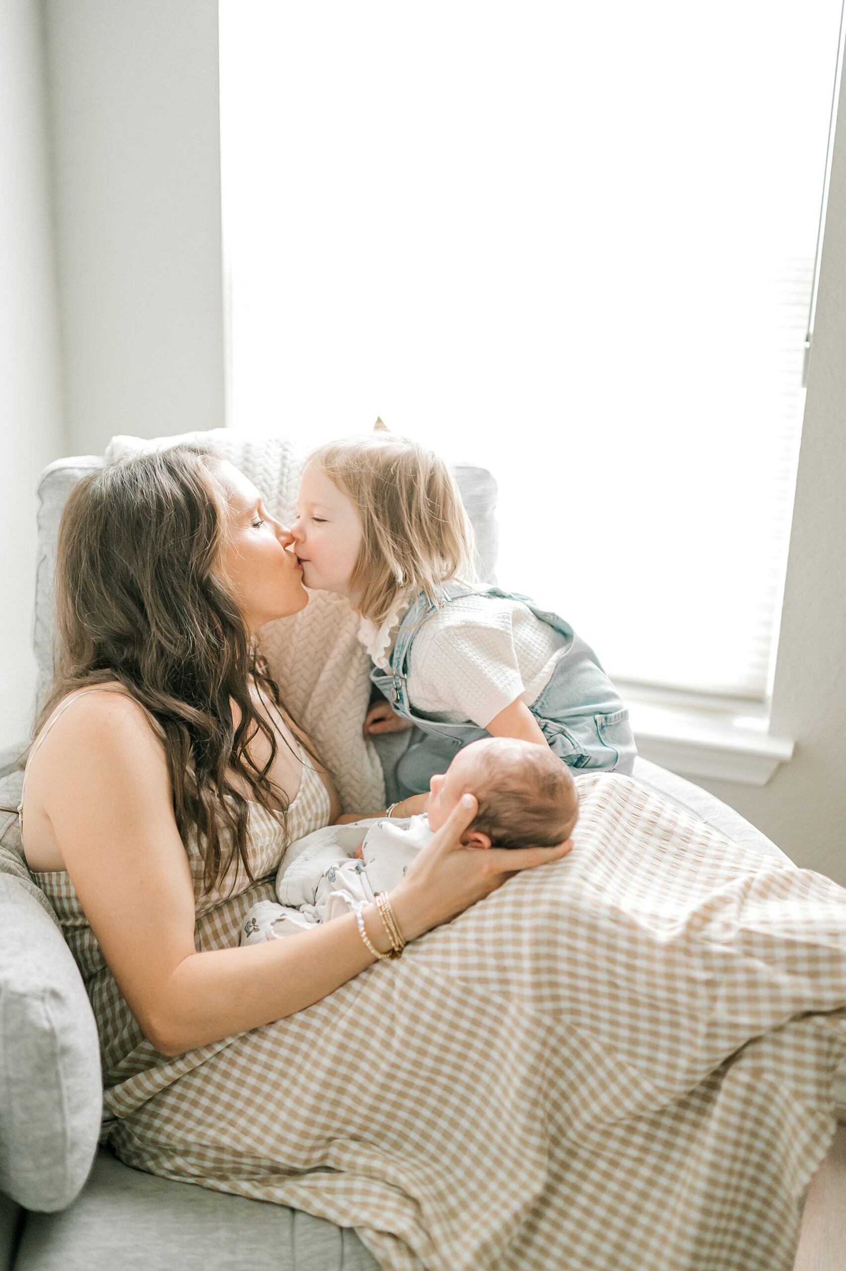 daughter kisses her mom who is holding newborn brother | Why I Love Including Toddlers in Newborn Sessions