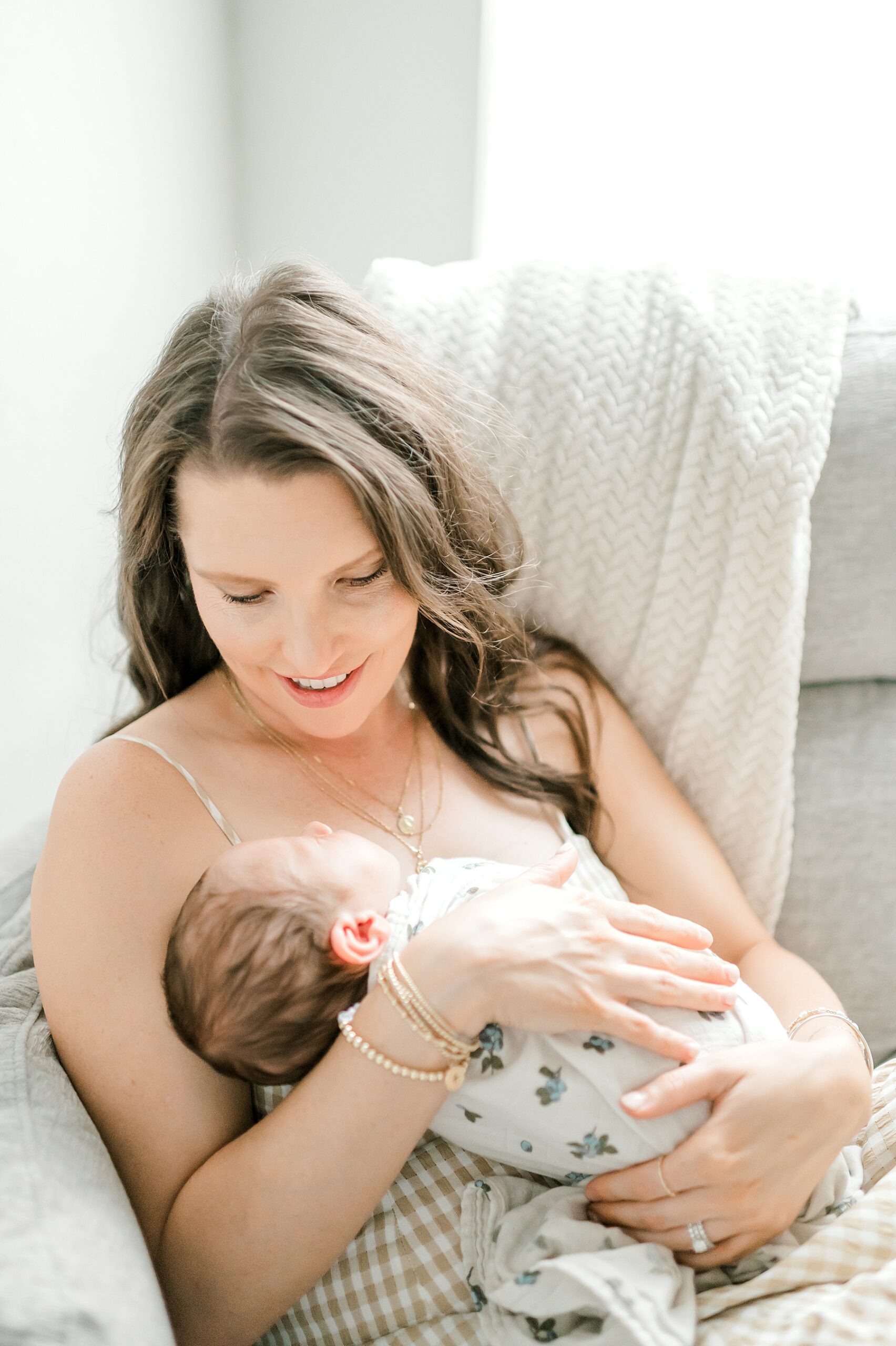 mom cradles newborn boy and looks down livingly at him
