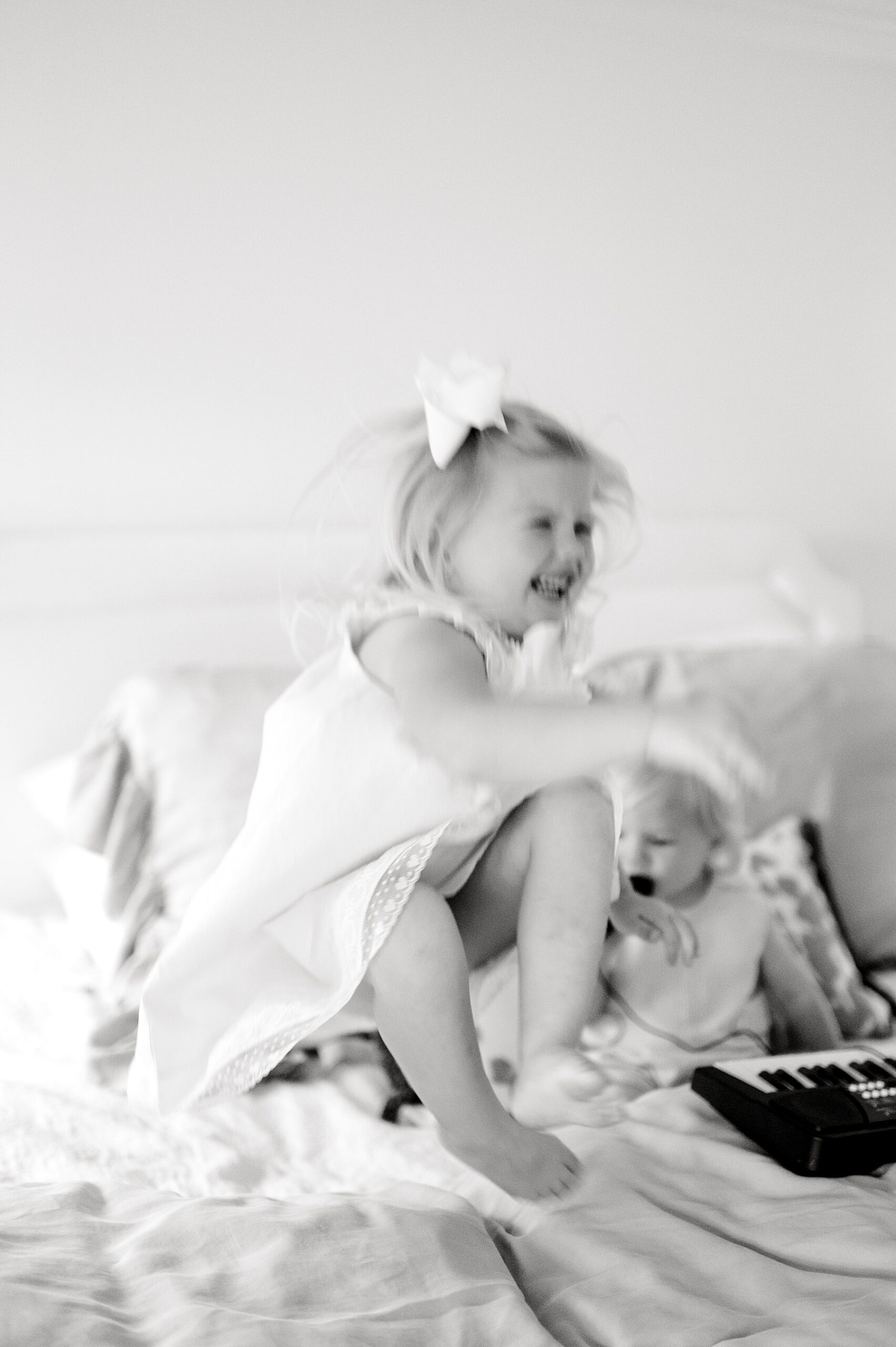 candid photo of little girl bouncing on bed during in-home newborn and family session 