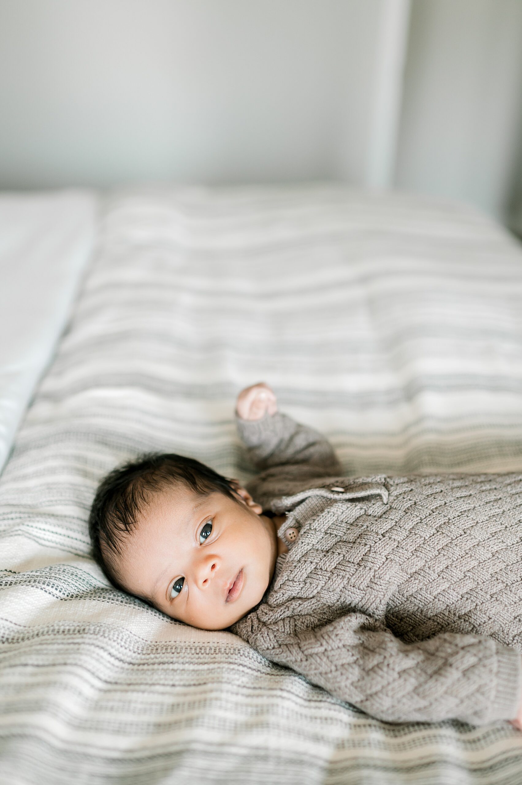 adorable and awake newborn lays on bed