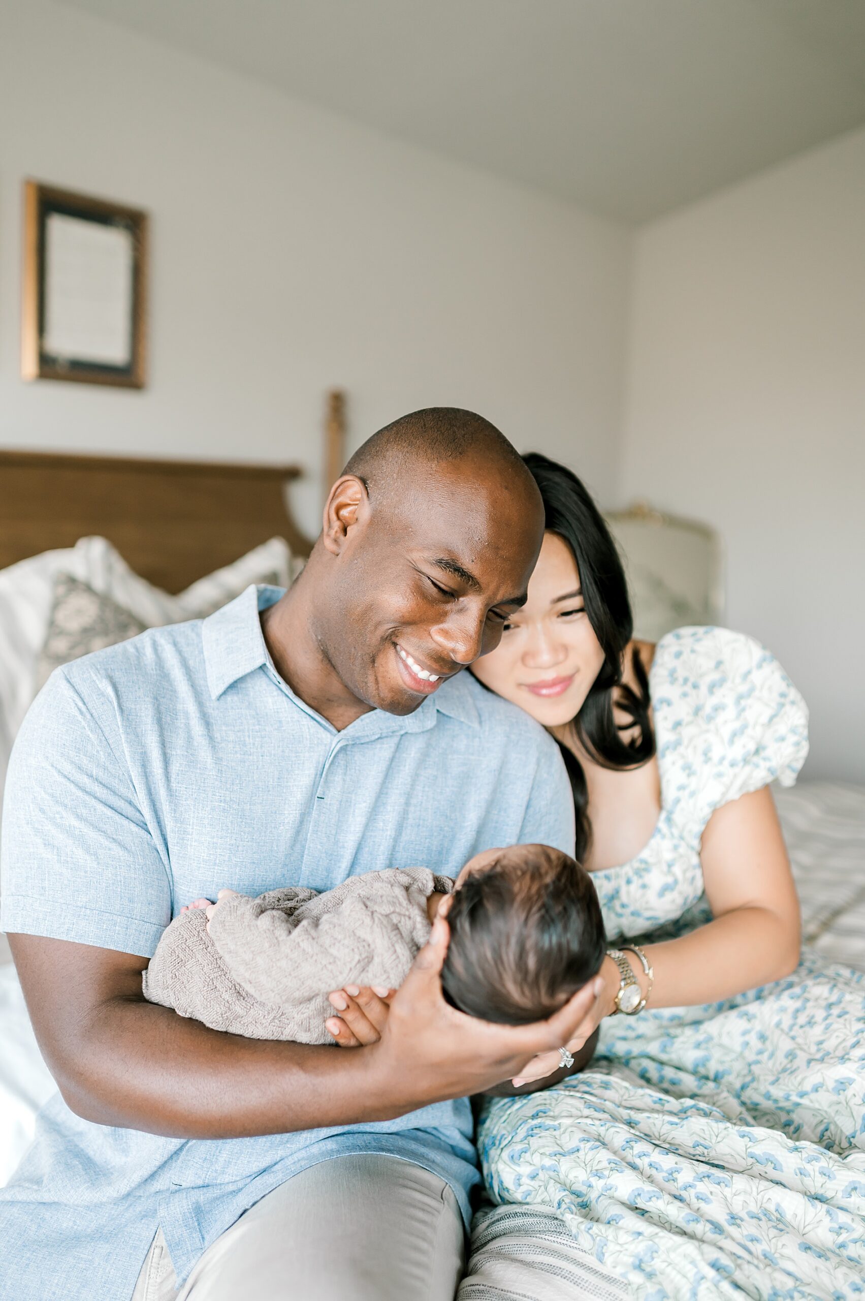 new parents look lovingly down at newborn 