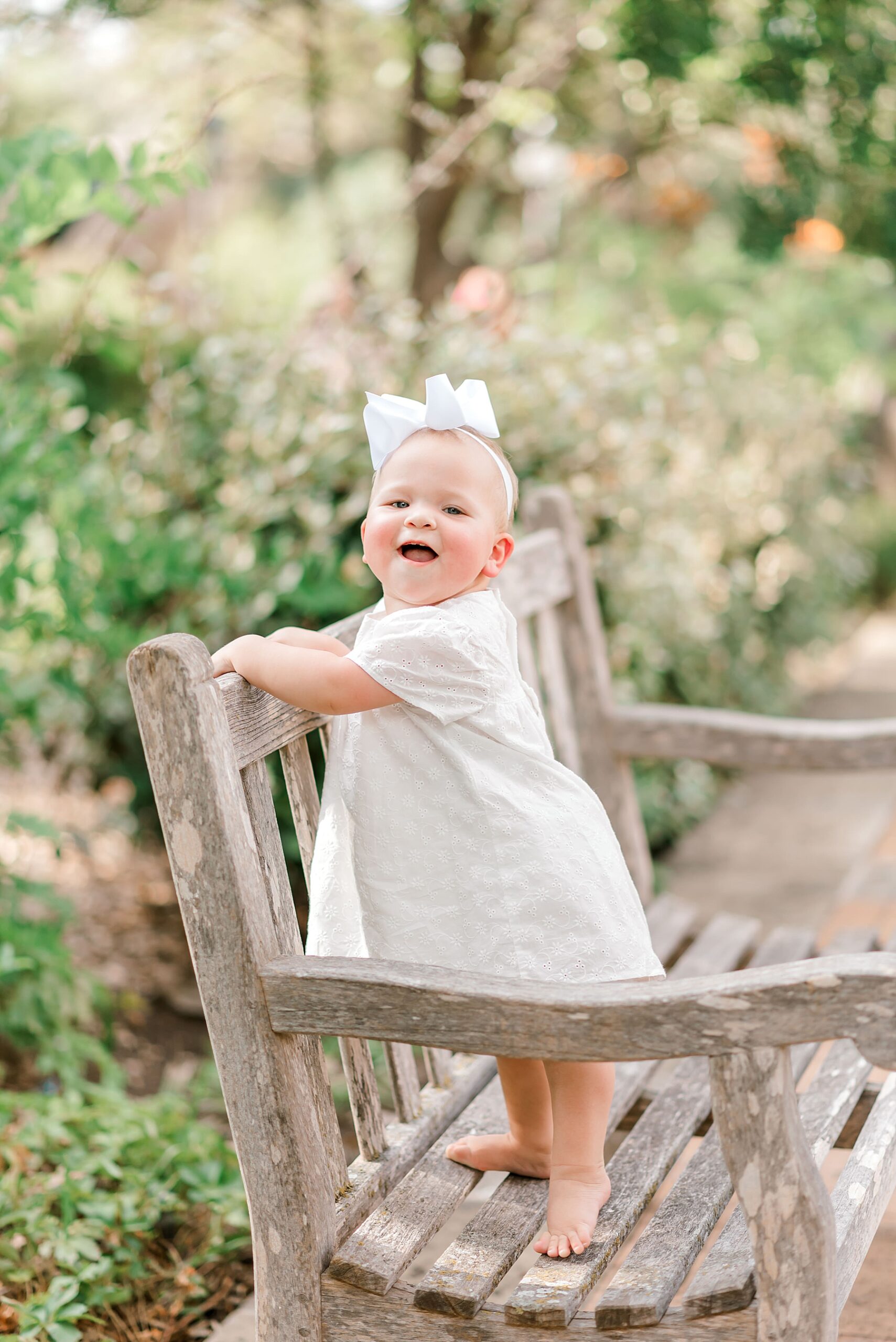 adorable little girl stands on wooden bench 