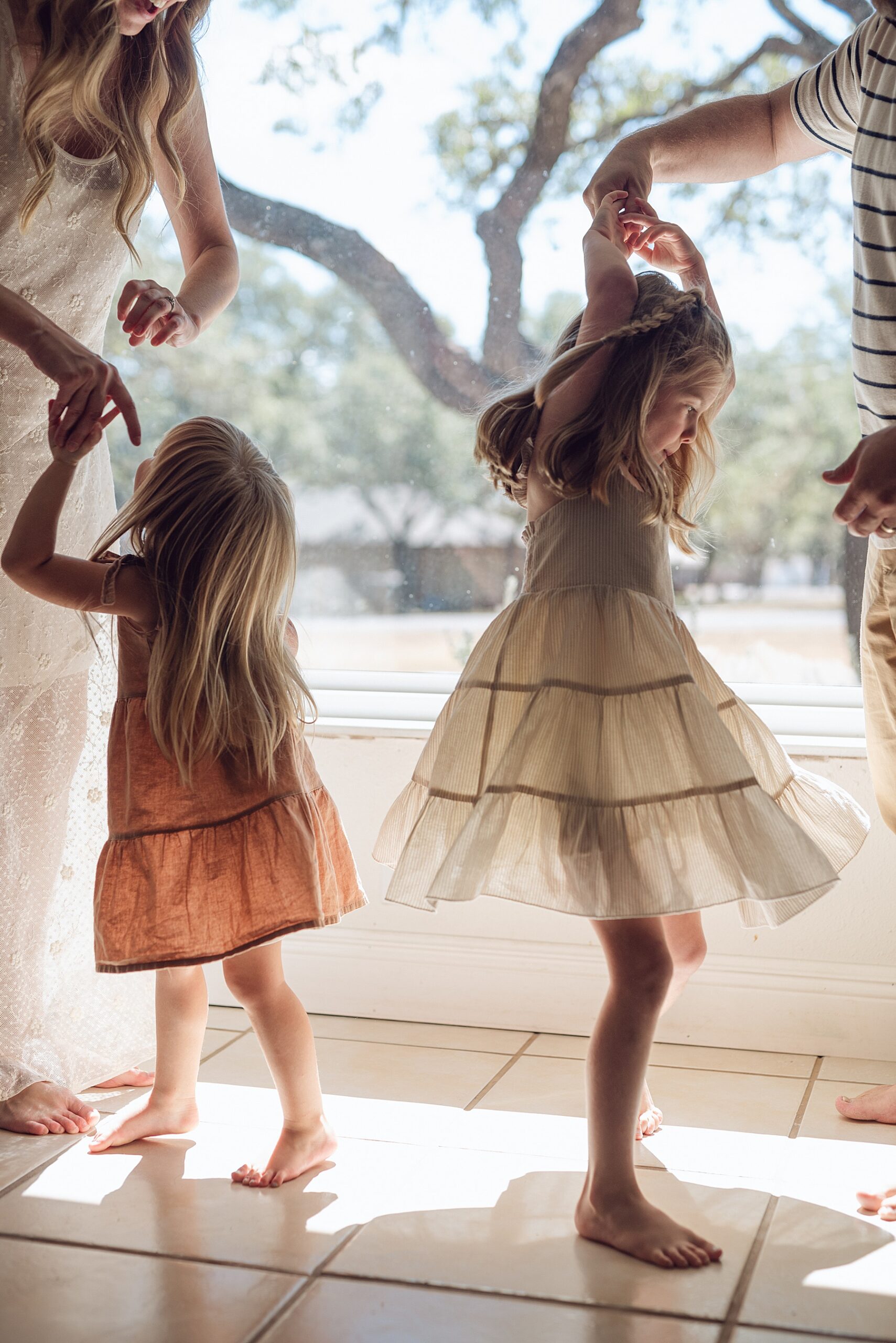 parents twirl their daughters around by the window 