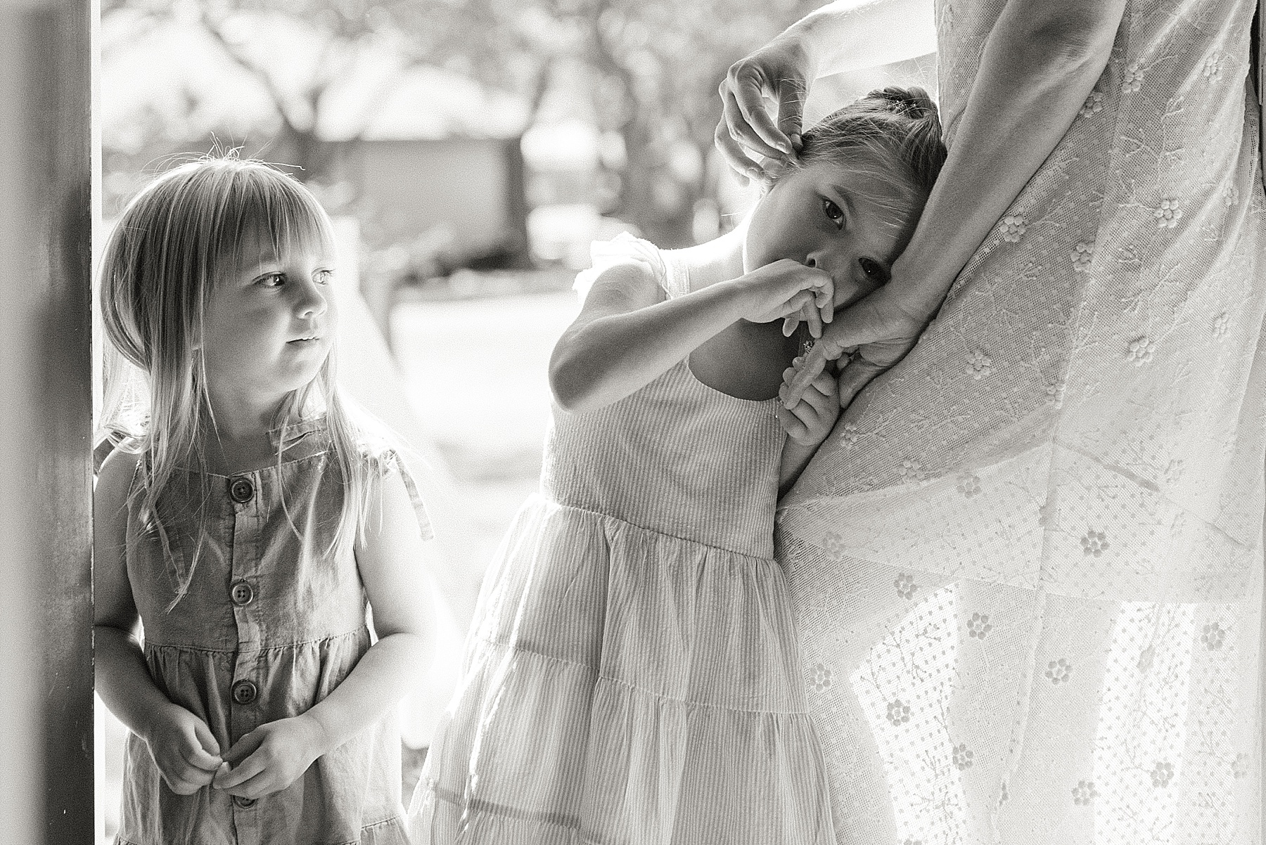 little girls lean on mom by the window 