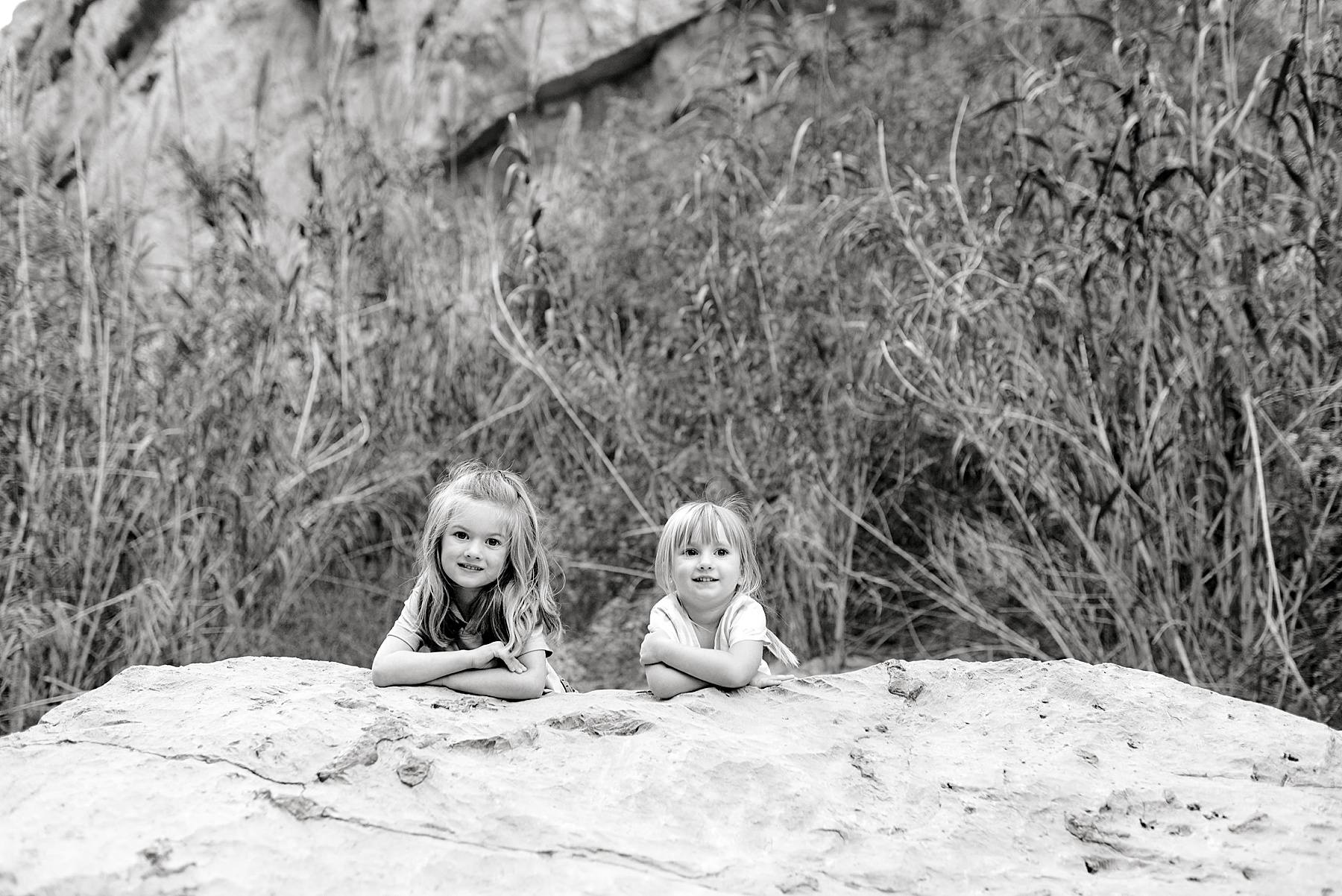 two little girls lay on rock