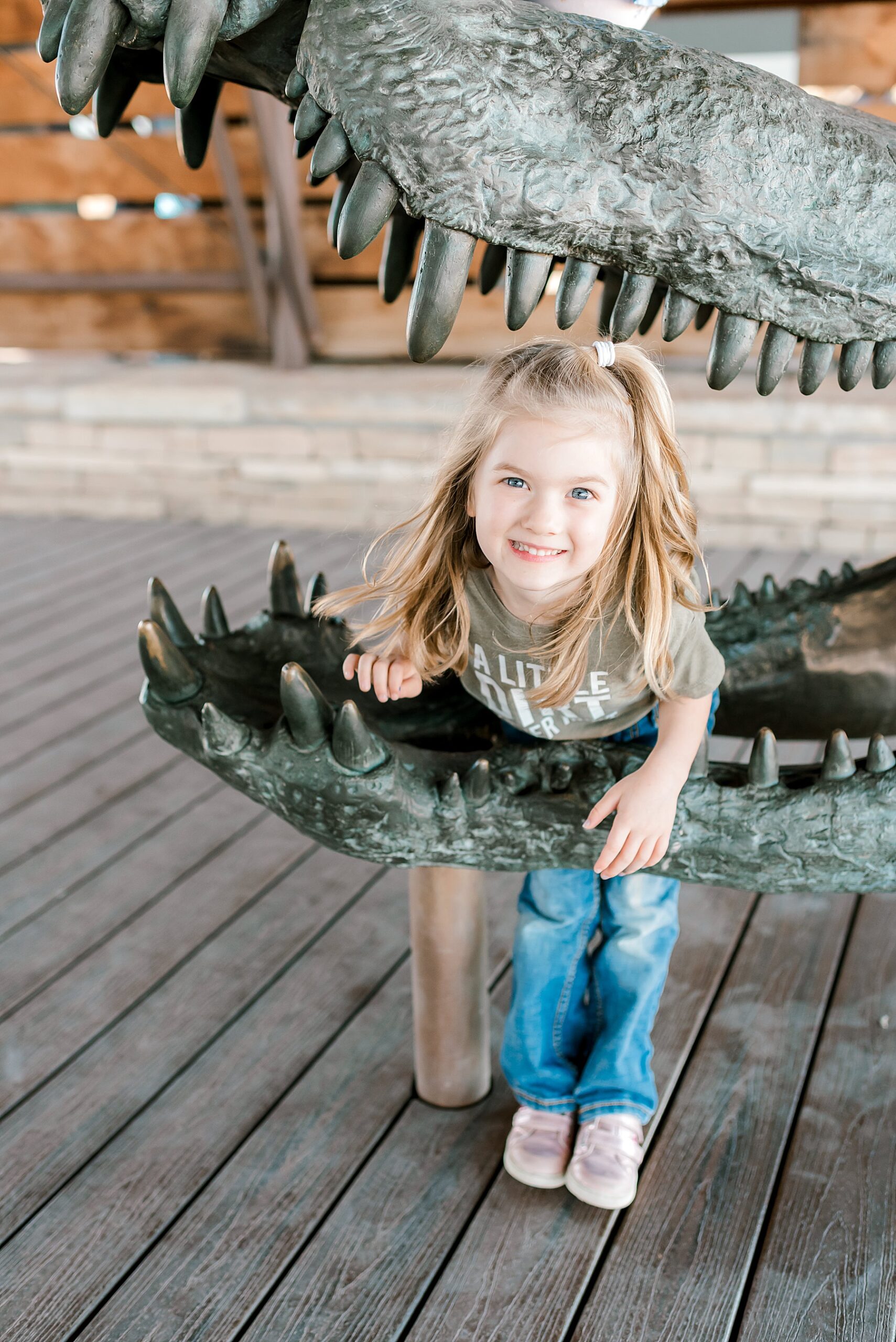 little girl in statue of dinosaur mouth