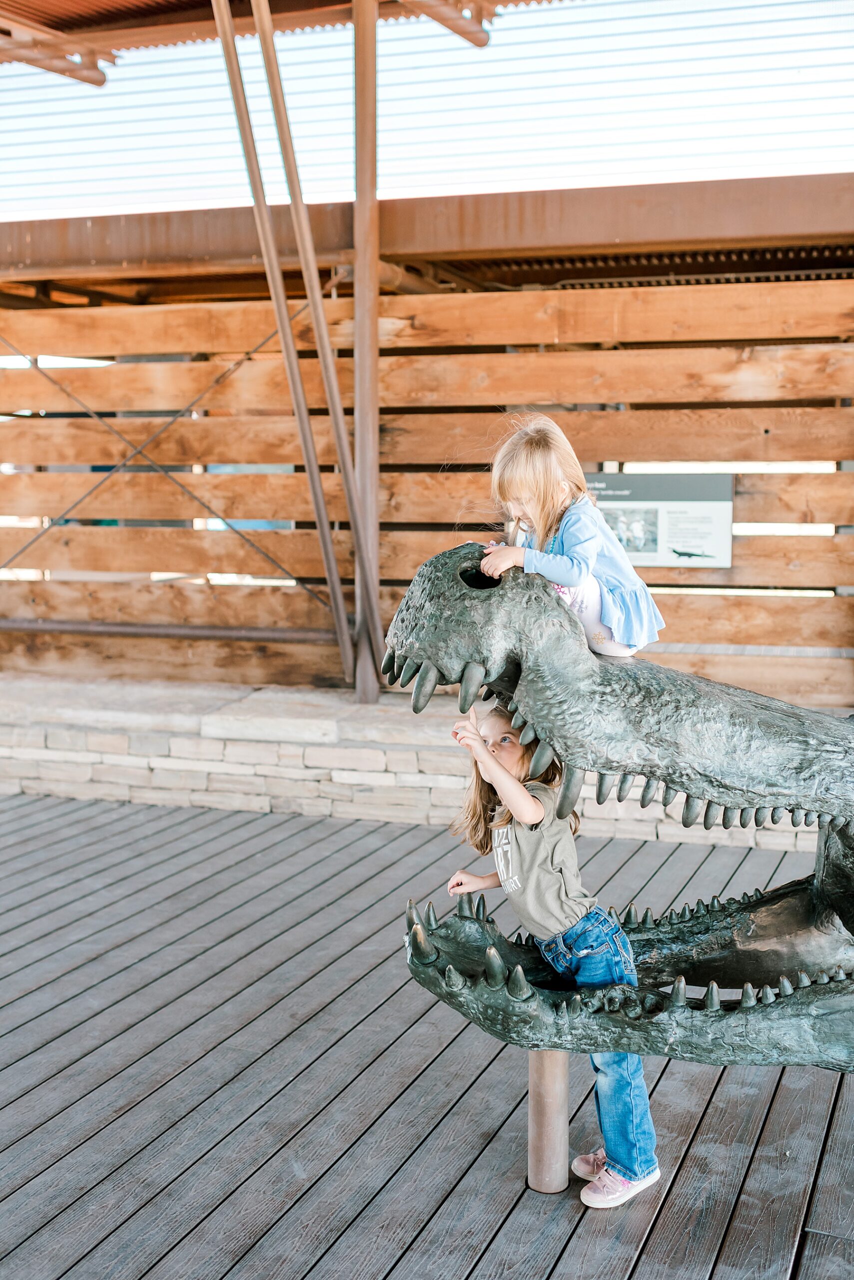 girls play on dinosaur statue