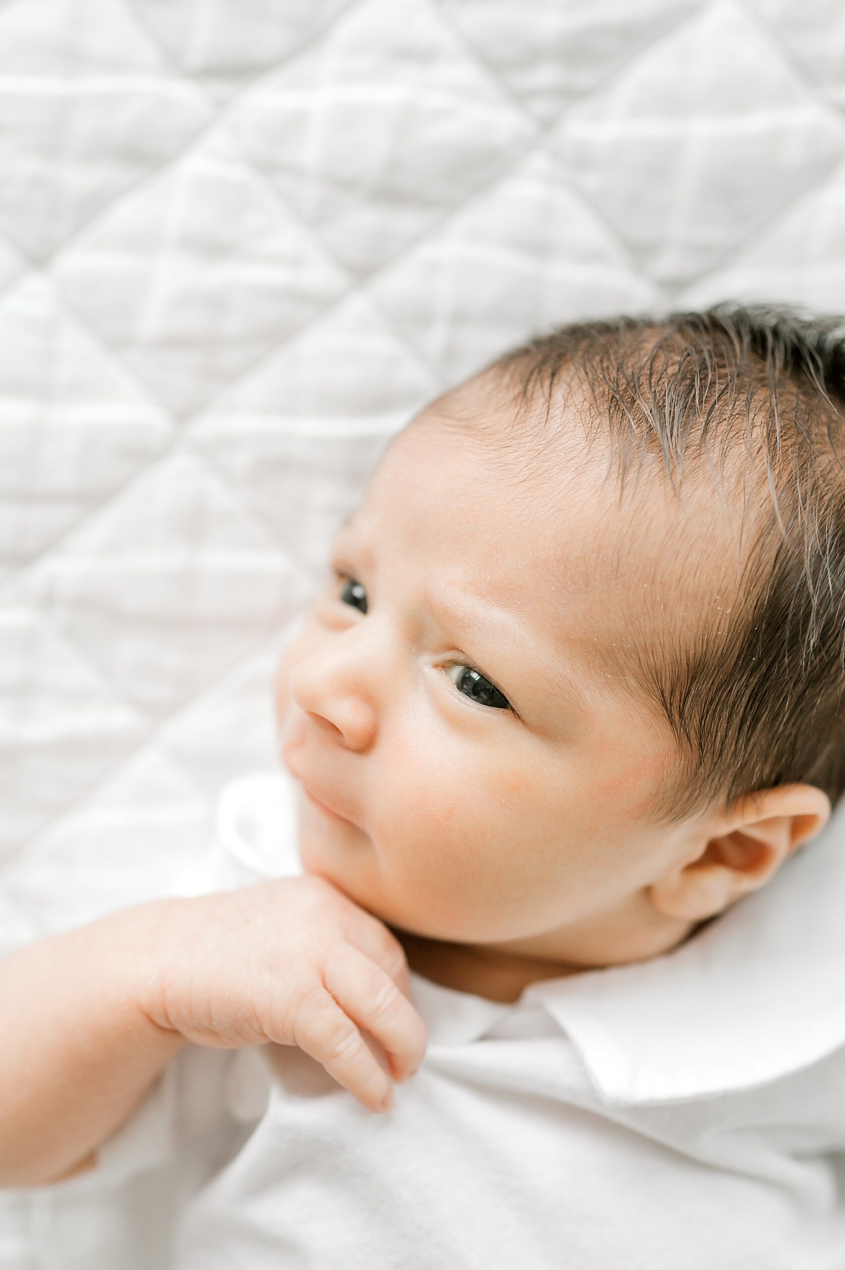 newborn boy lays on white blanket
