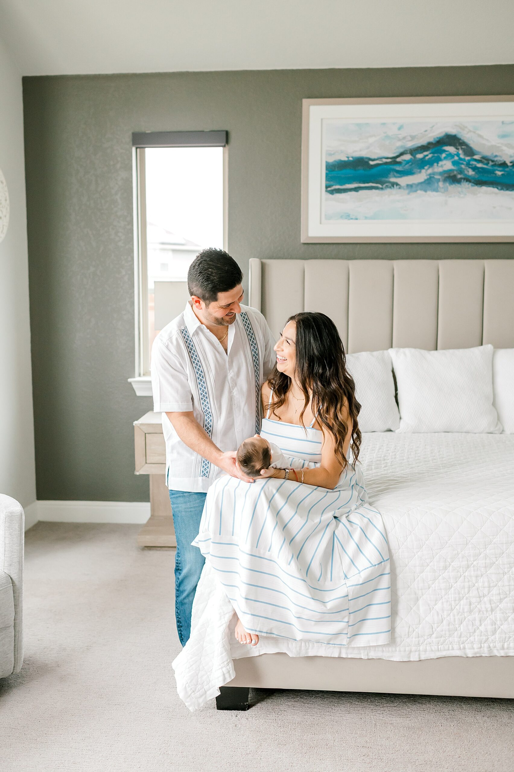 parents hold newborn in master bedroom