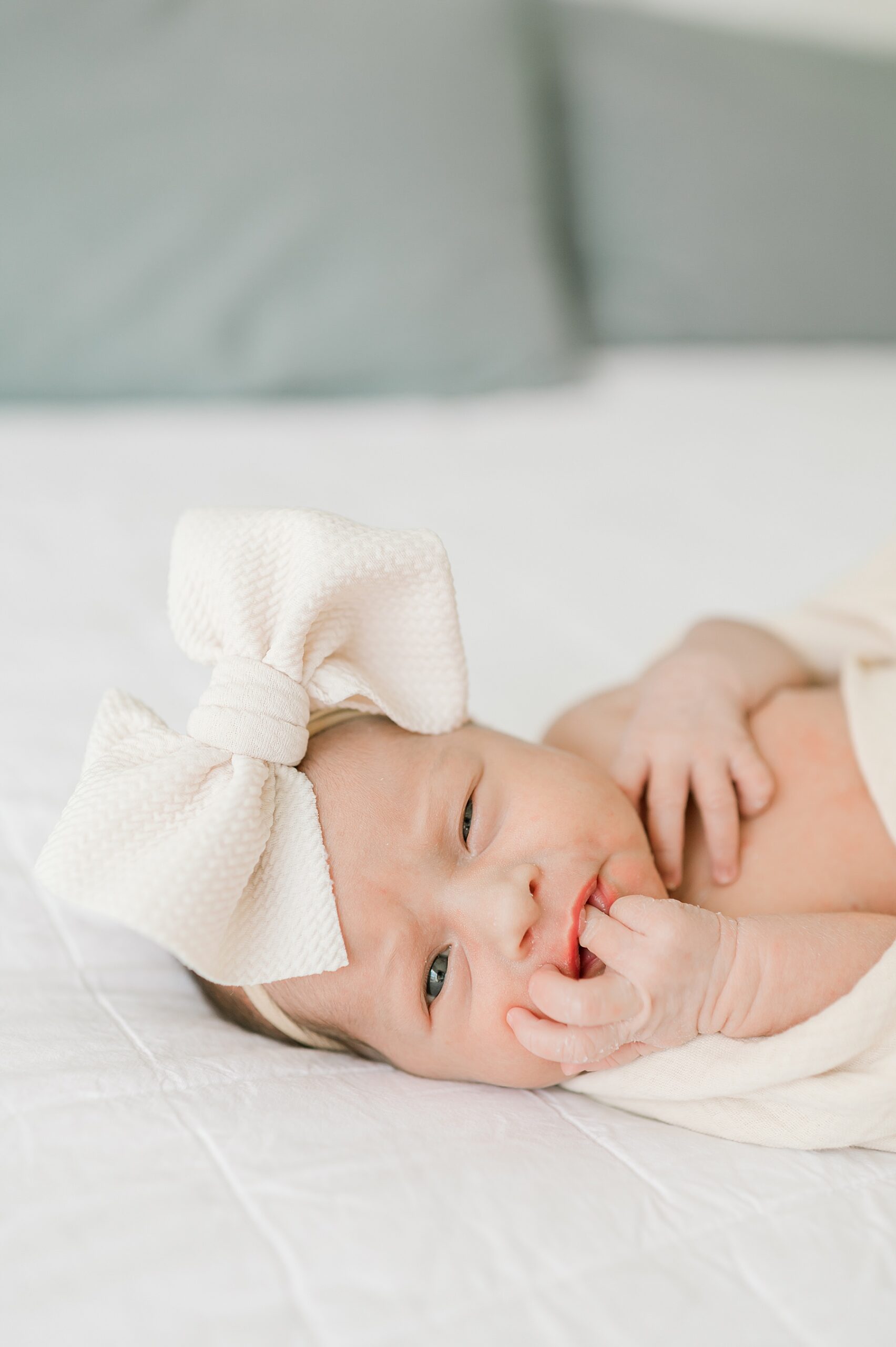 newborn girl in loosened swaddle with bow