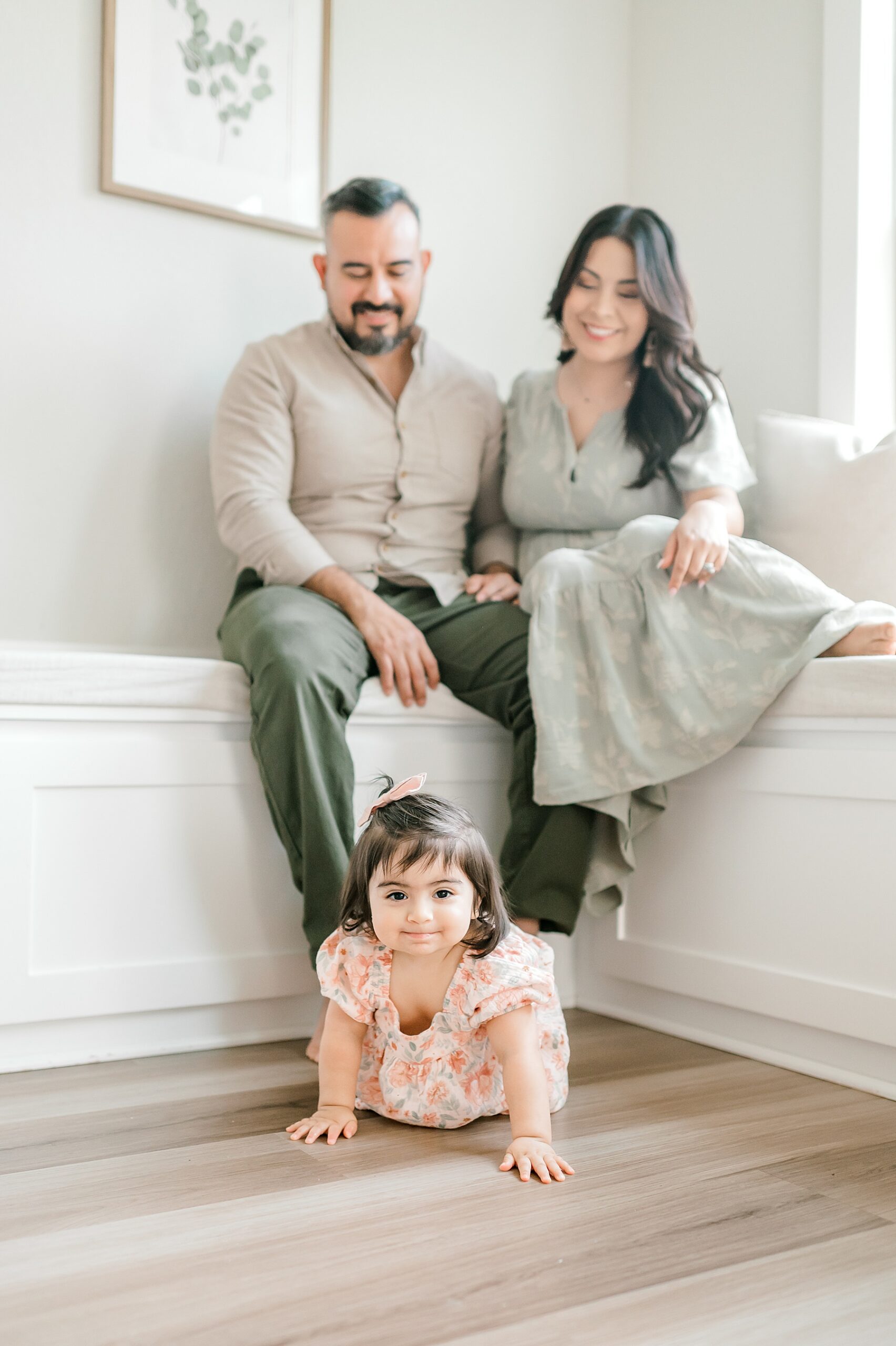parents sit while little girl crawls on floor