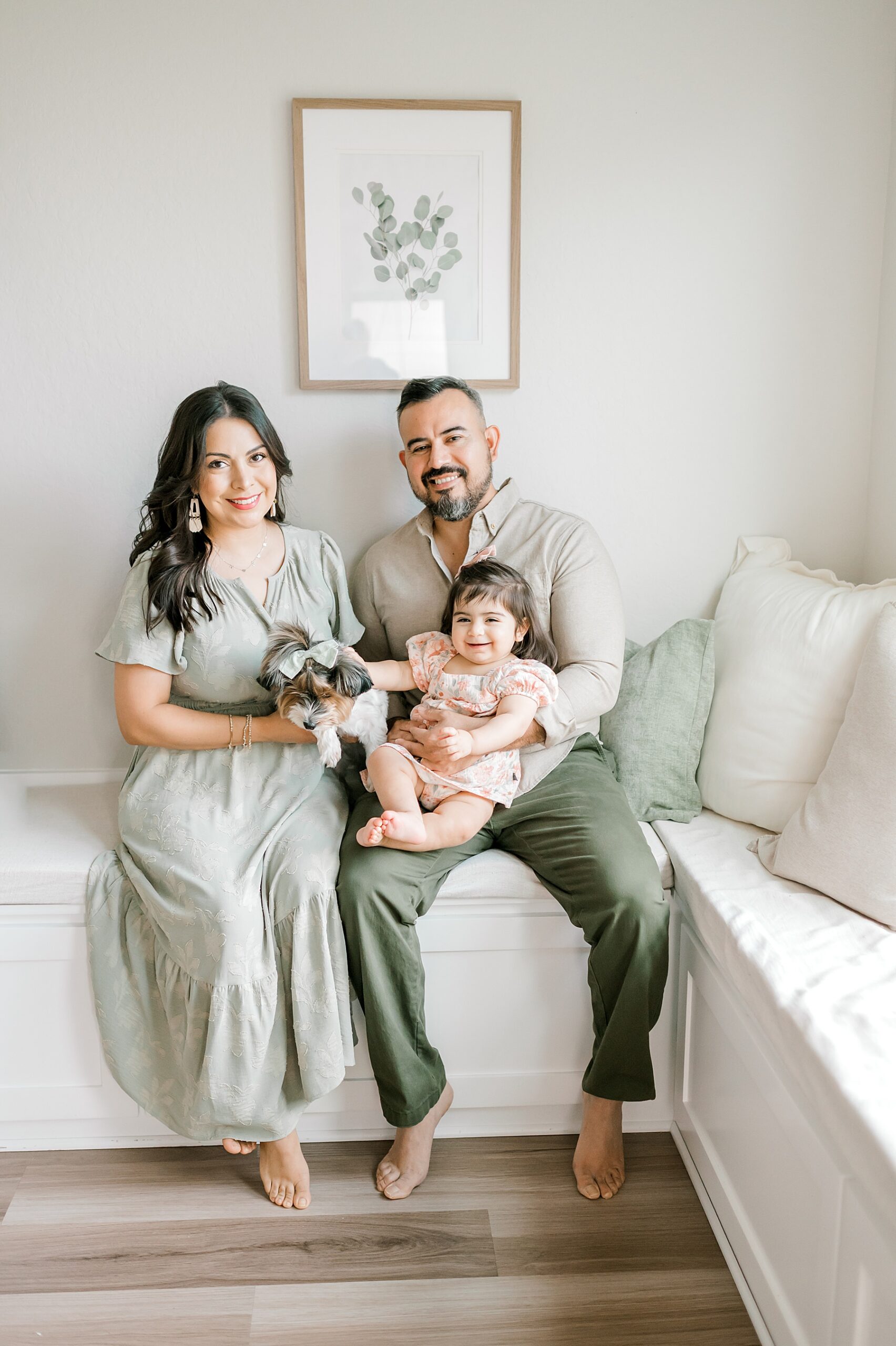 family of three with their dog sit together during in-home session