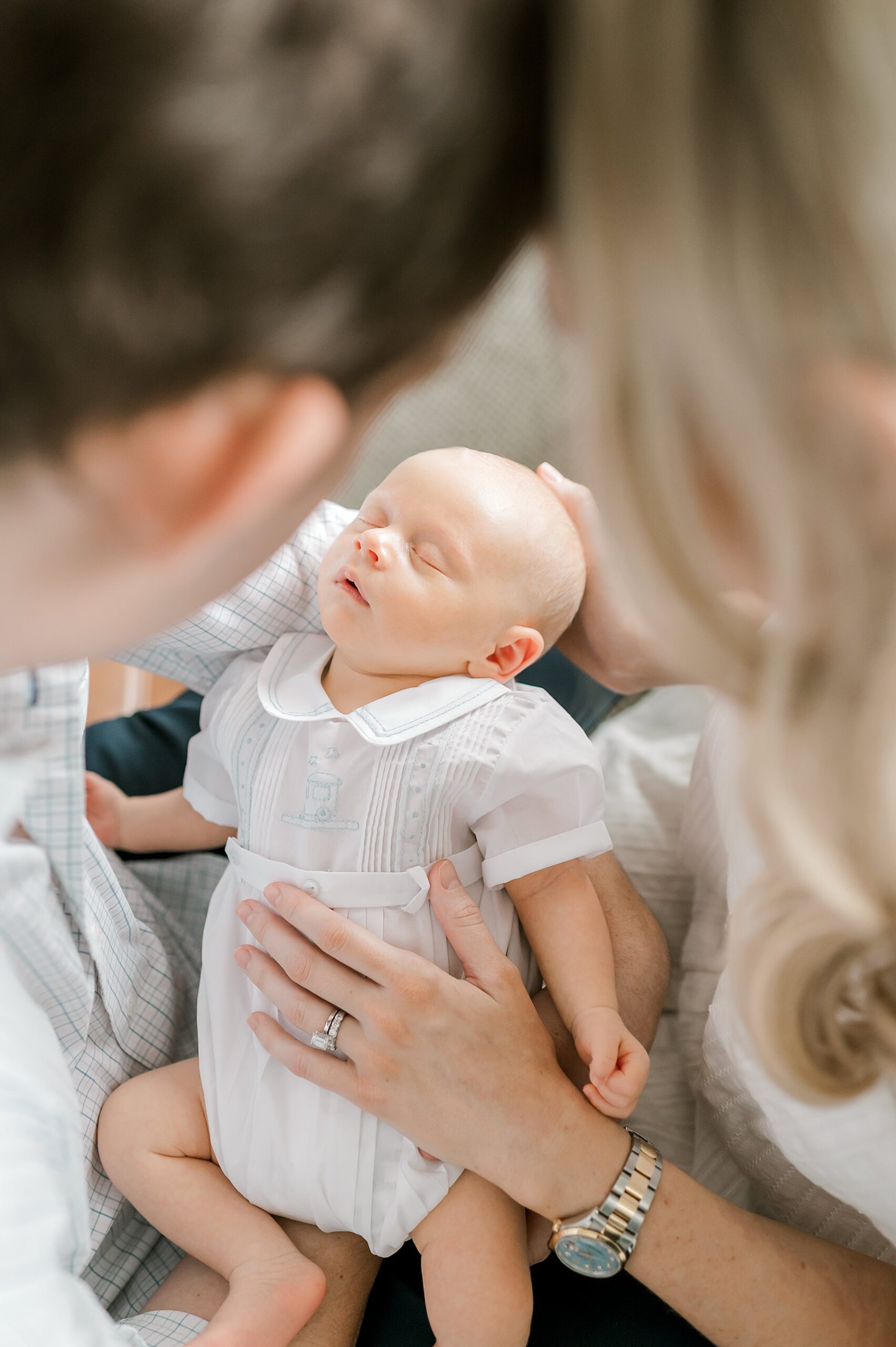 parents look down sleeping newborn 