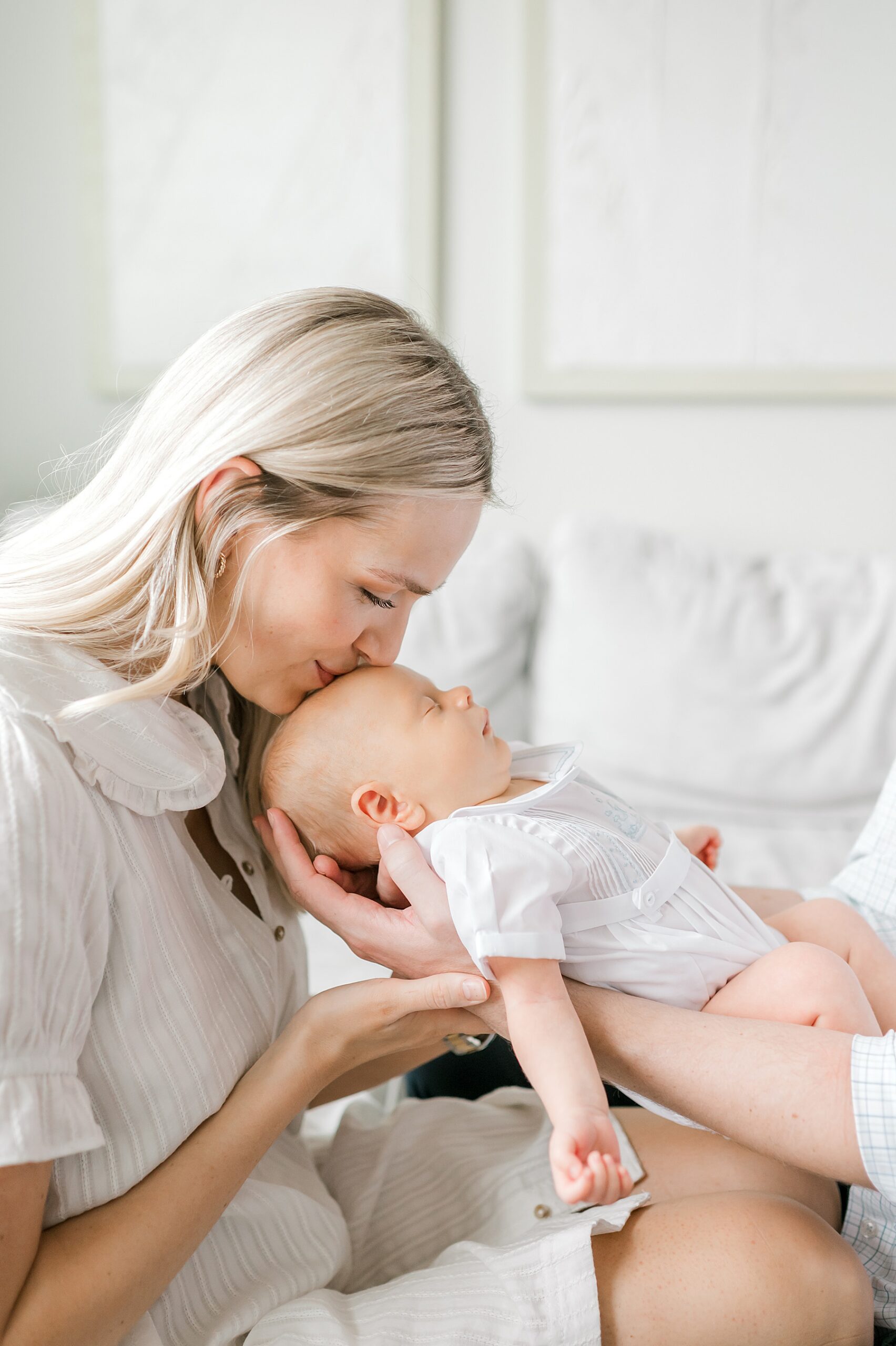mom kisses newborn's head as he sleeps