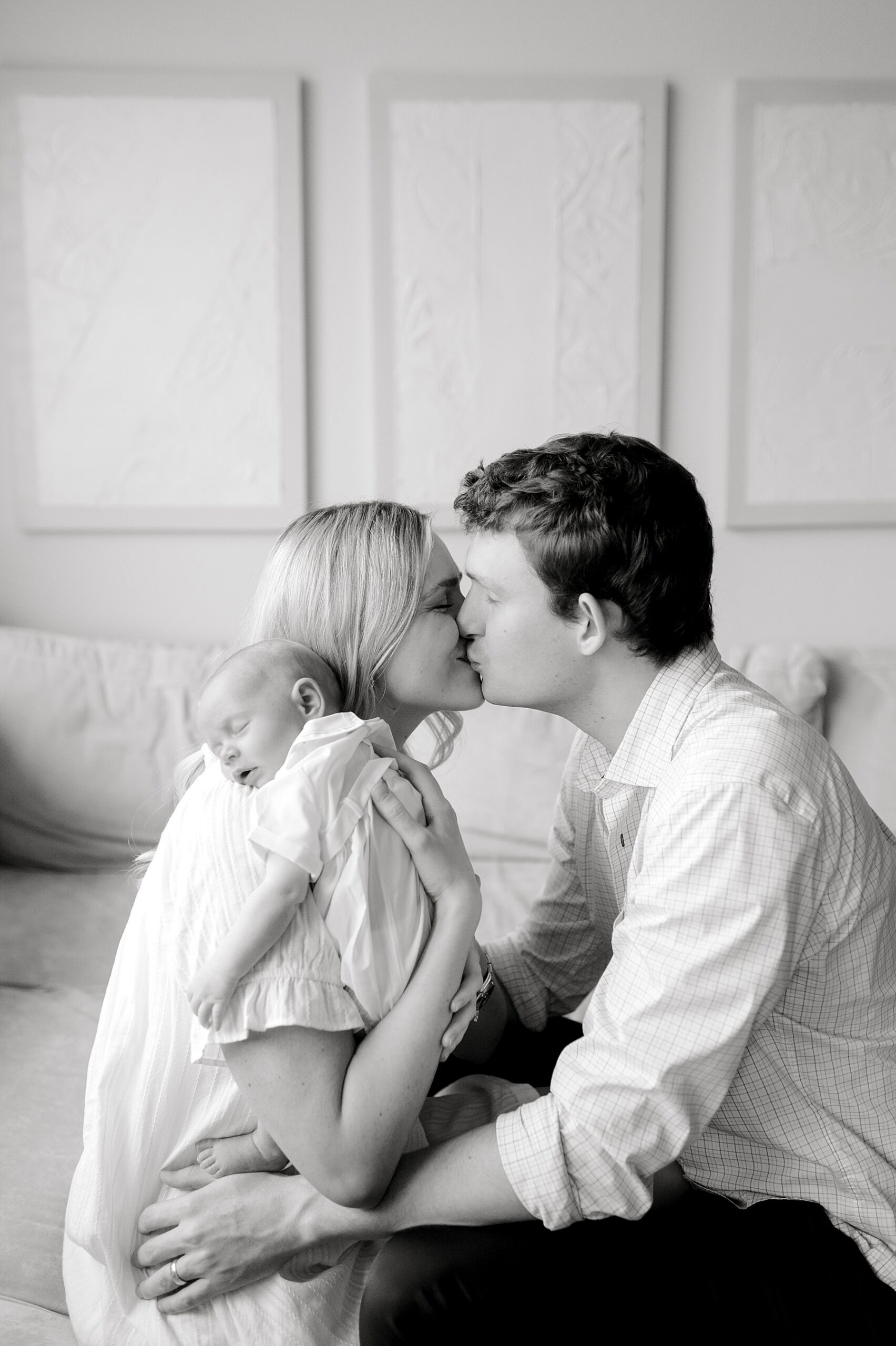parents kiss as newborn sleeps 