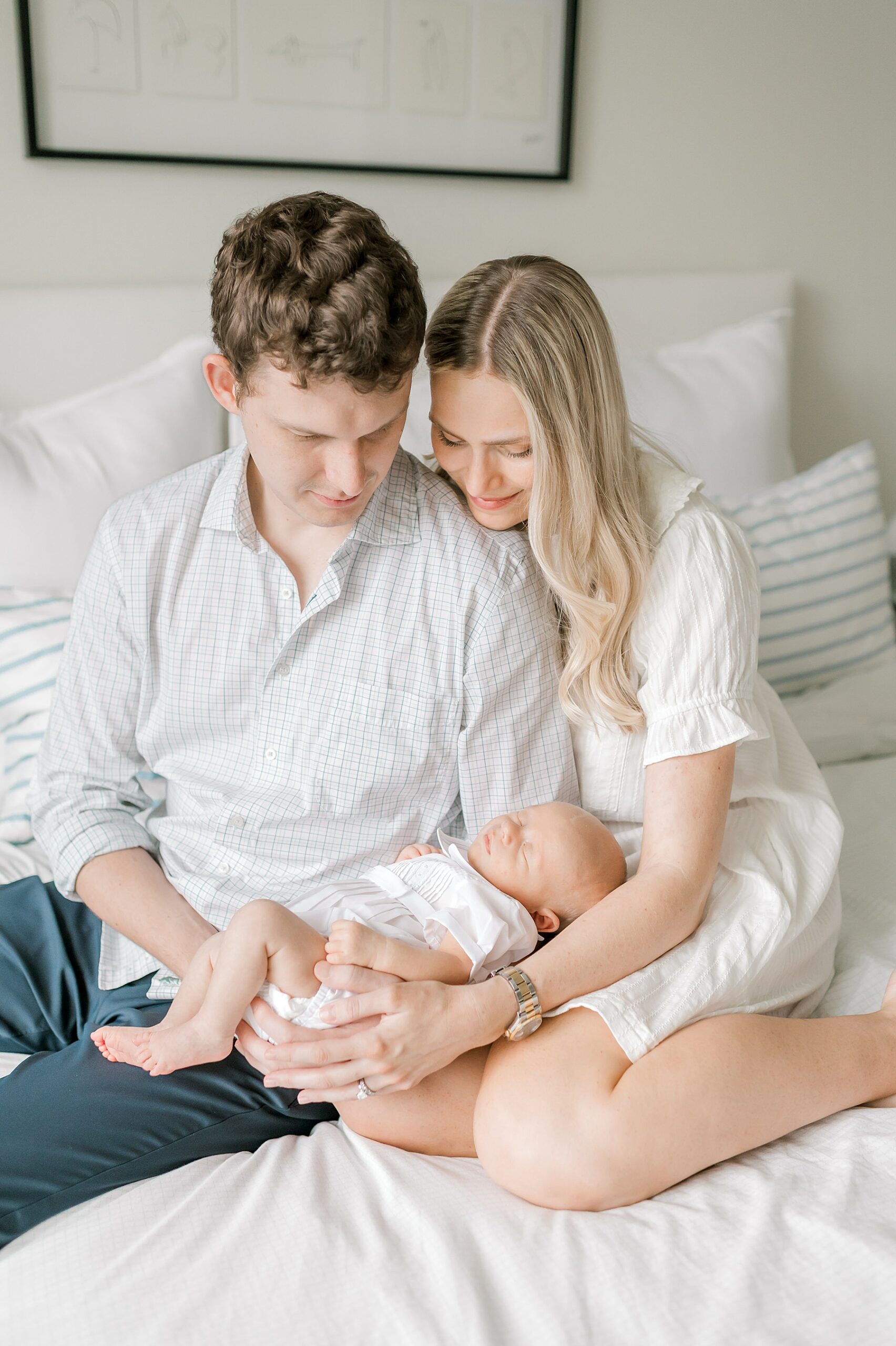 new parents hold newborn on bed during in-home lifestyle newborn session