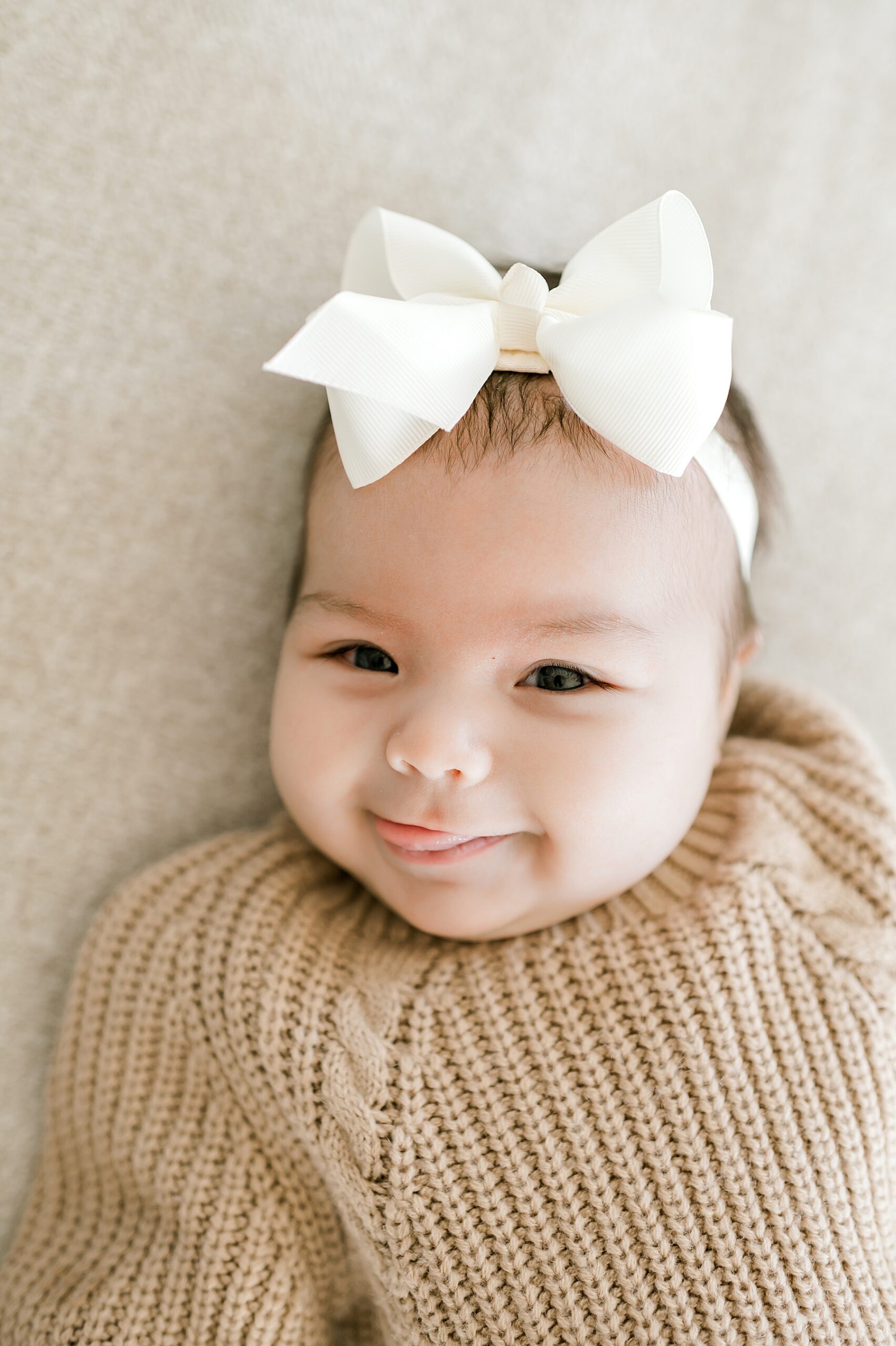 adorable newborn girl in knit sweater and white bow