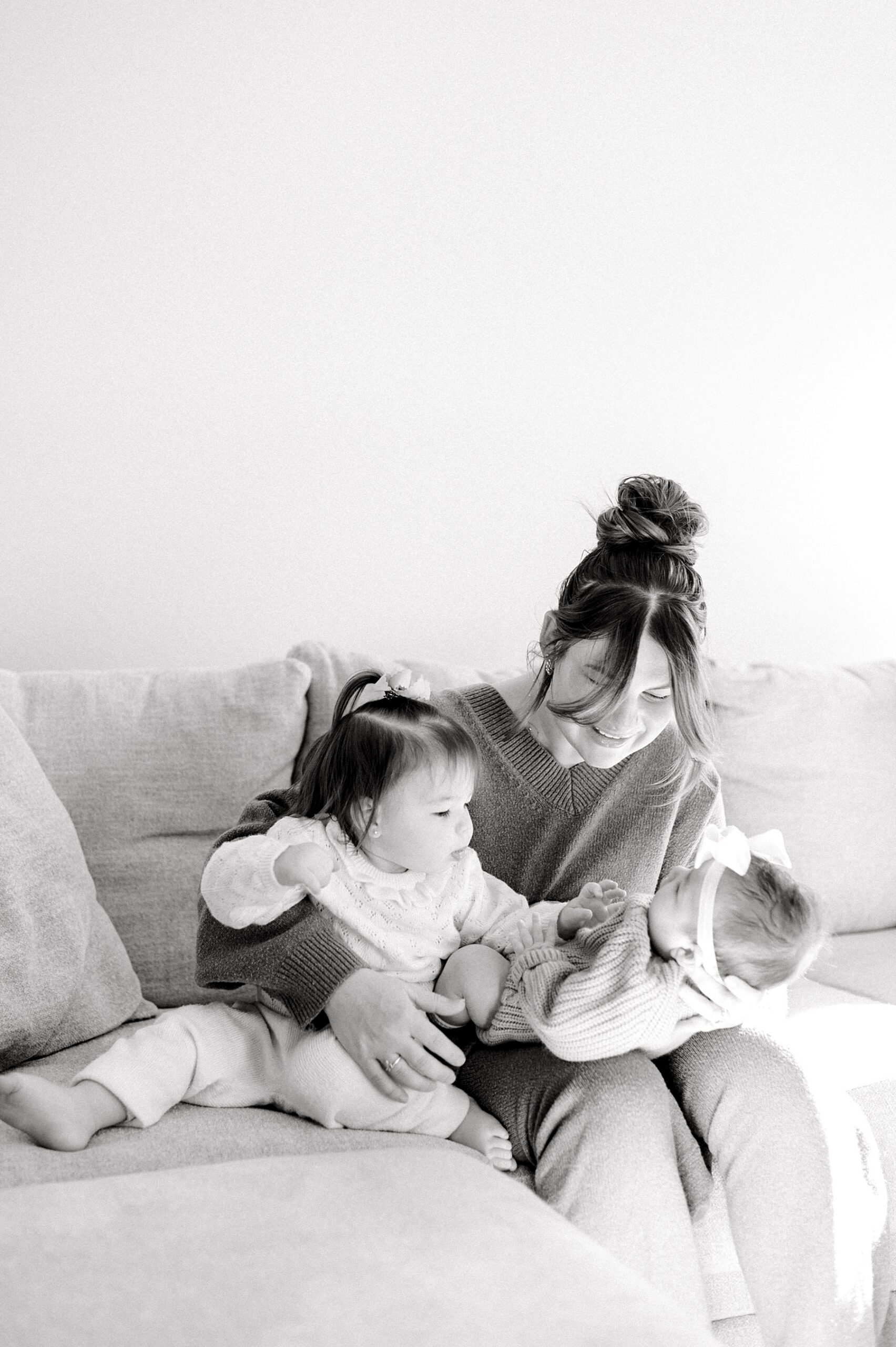 mom cradles newborn with toddler sitting with her 