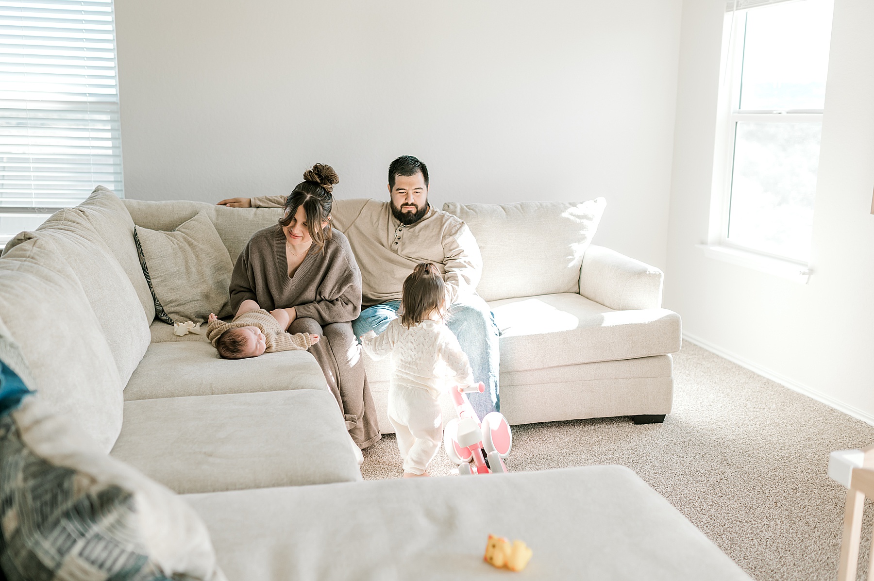 family sits in living room by large windows 