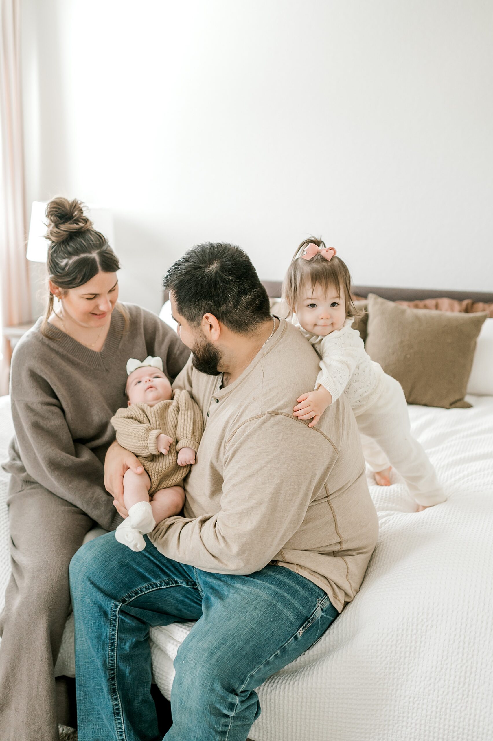 parents sit on bed holding newborn girl 
