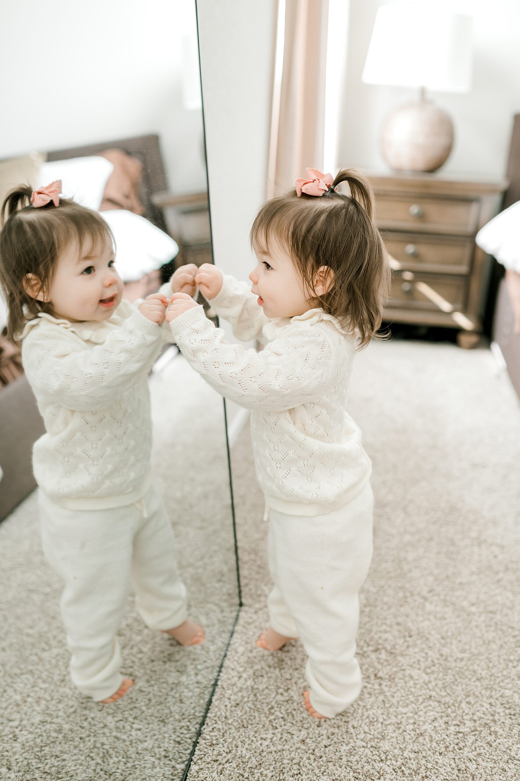 toddler girl looks at her reflection in mirror