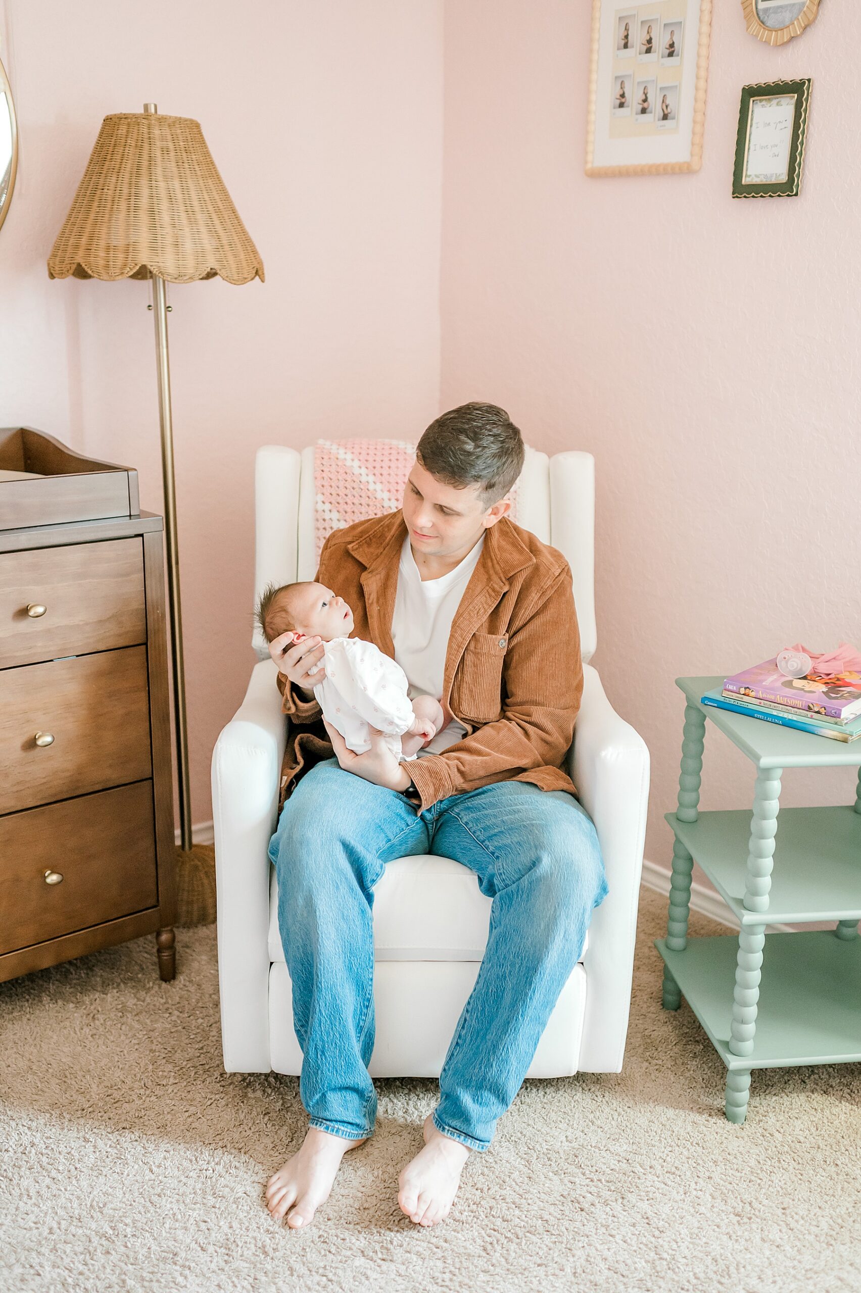 dad holds newborn in chair in nursery 