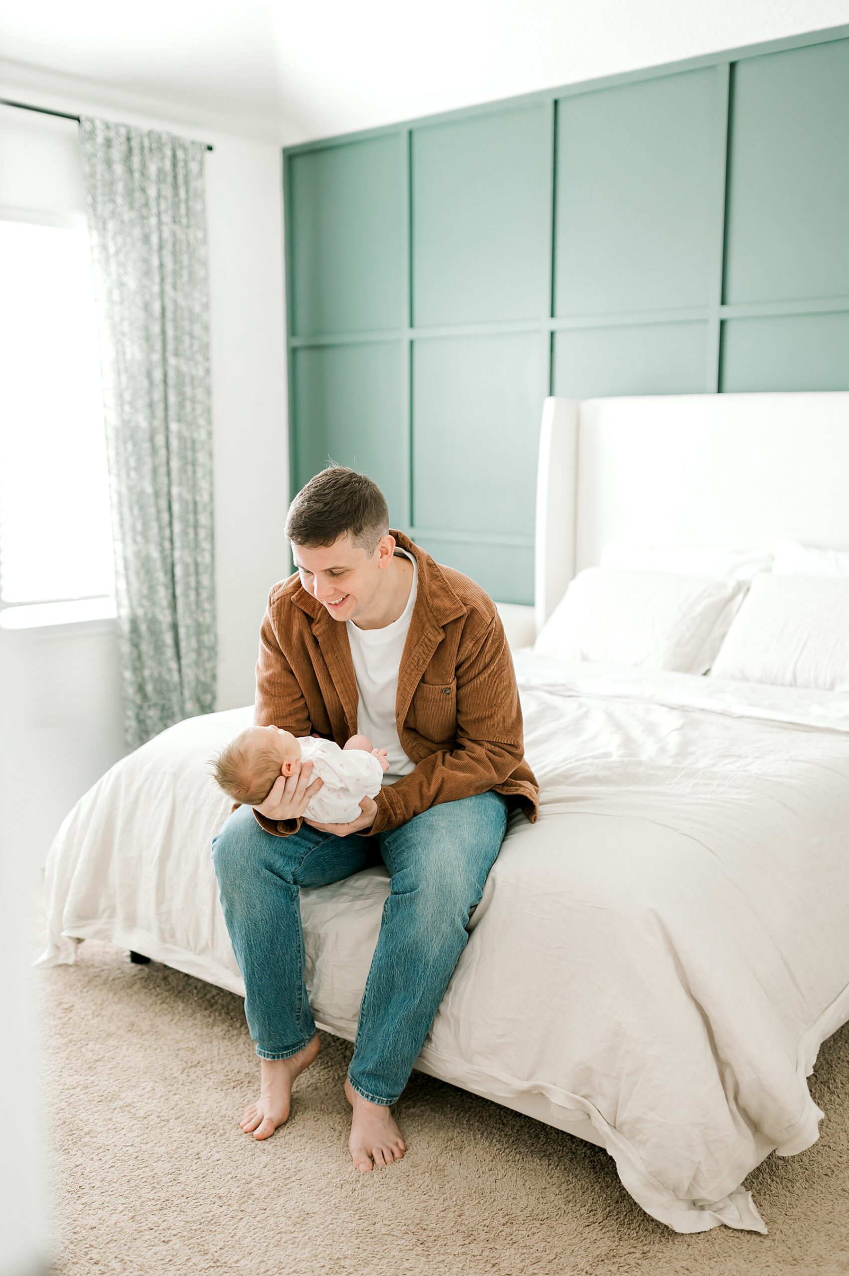 dad holds baby daughter while sitting on bed