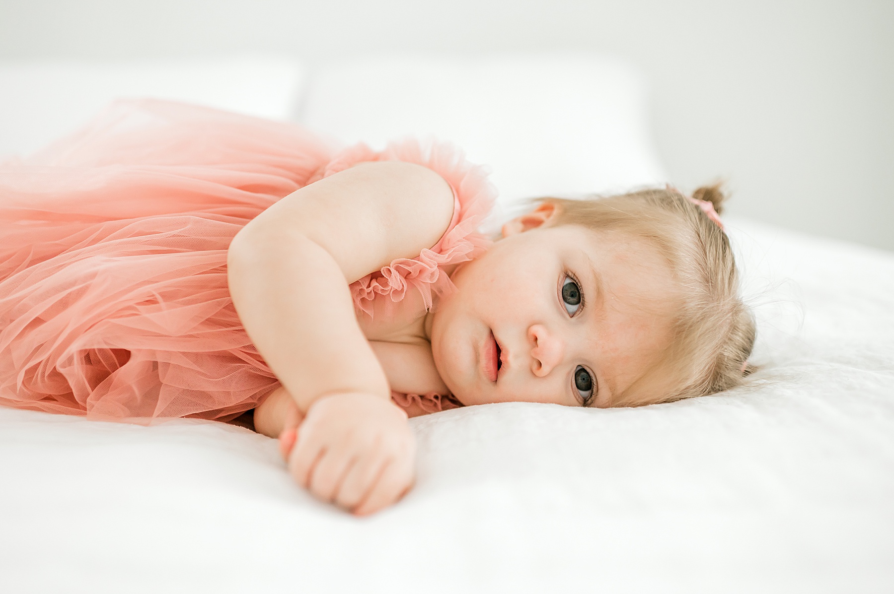 little girl lays on bed during 1 year milestone session