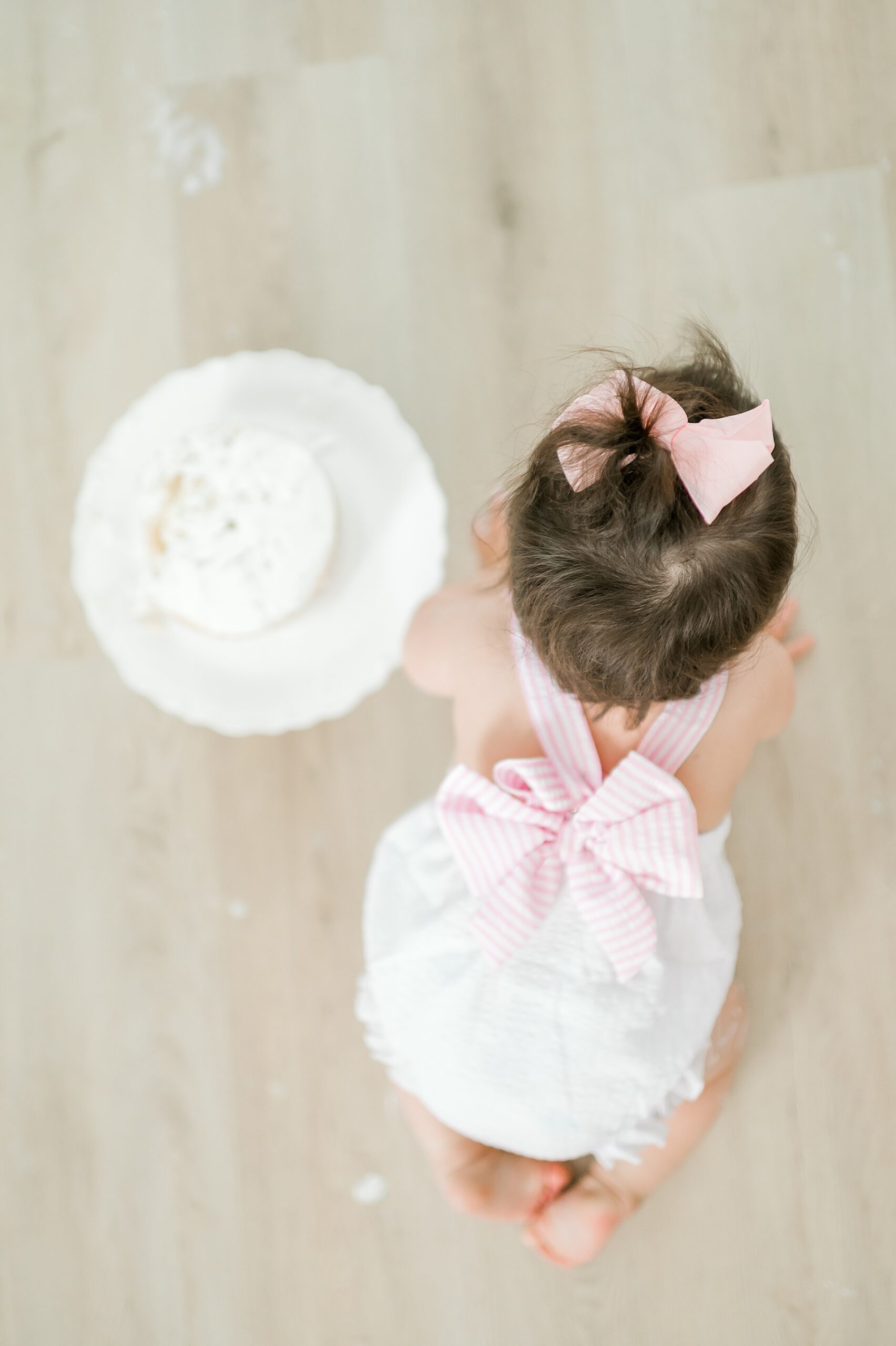 one year old little girl crawls around floor next to cake 
